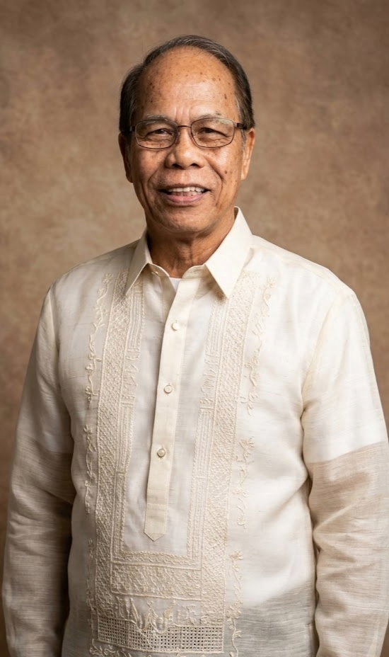 Older man with glasses, smiling, wearing a traditional Filipino barong tagalog shirt in a portrait against a brown background.