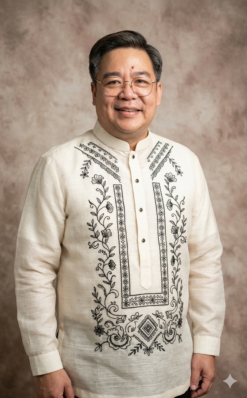 A man wearing glasses and a cream-colored barong shirt with black embroidery, standing in front of a beige mottled background, smiling at the camera.