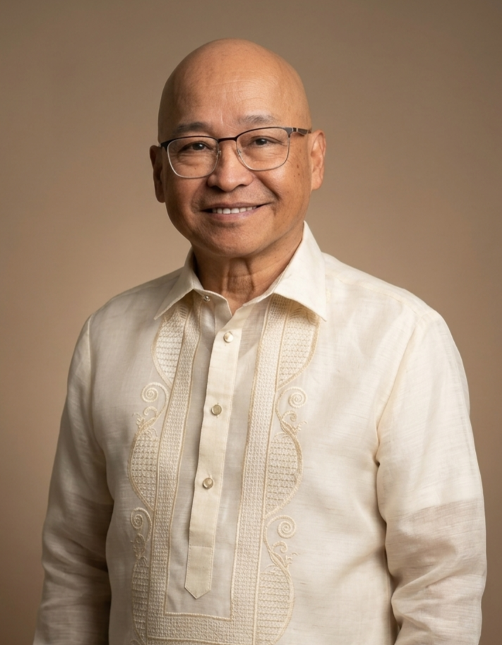 A smiling middle-aged man wearing glasses and a traditional Filipino Barong Tagalog shirt, standing against a plain background.