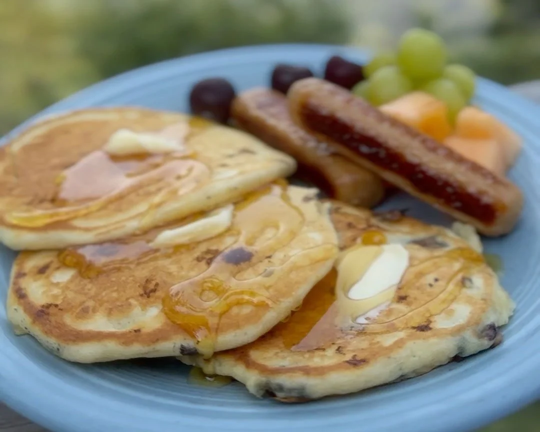 Pancakes with local maple syrup, breakfast sausages, and fruit