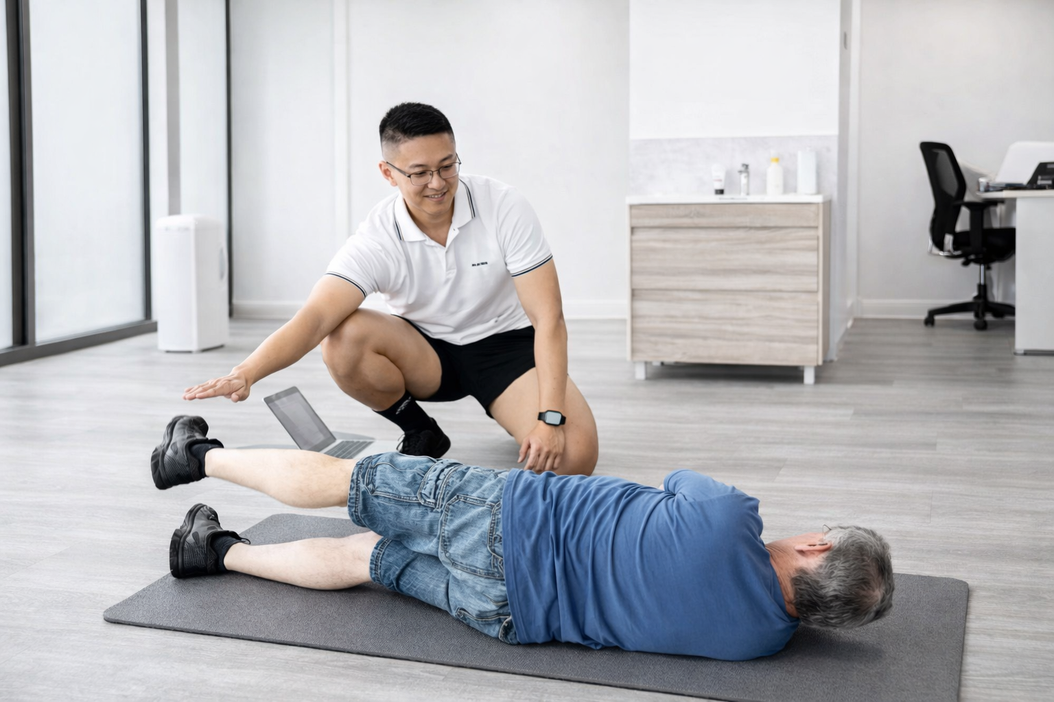 Exercise Physiologist wearing white polo guiding floor exercises with a patient
