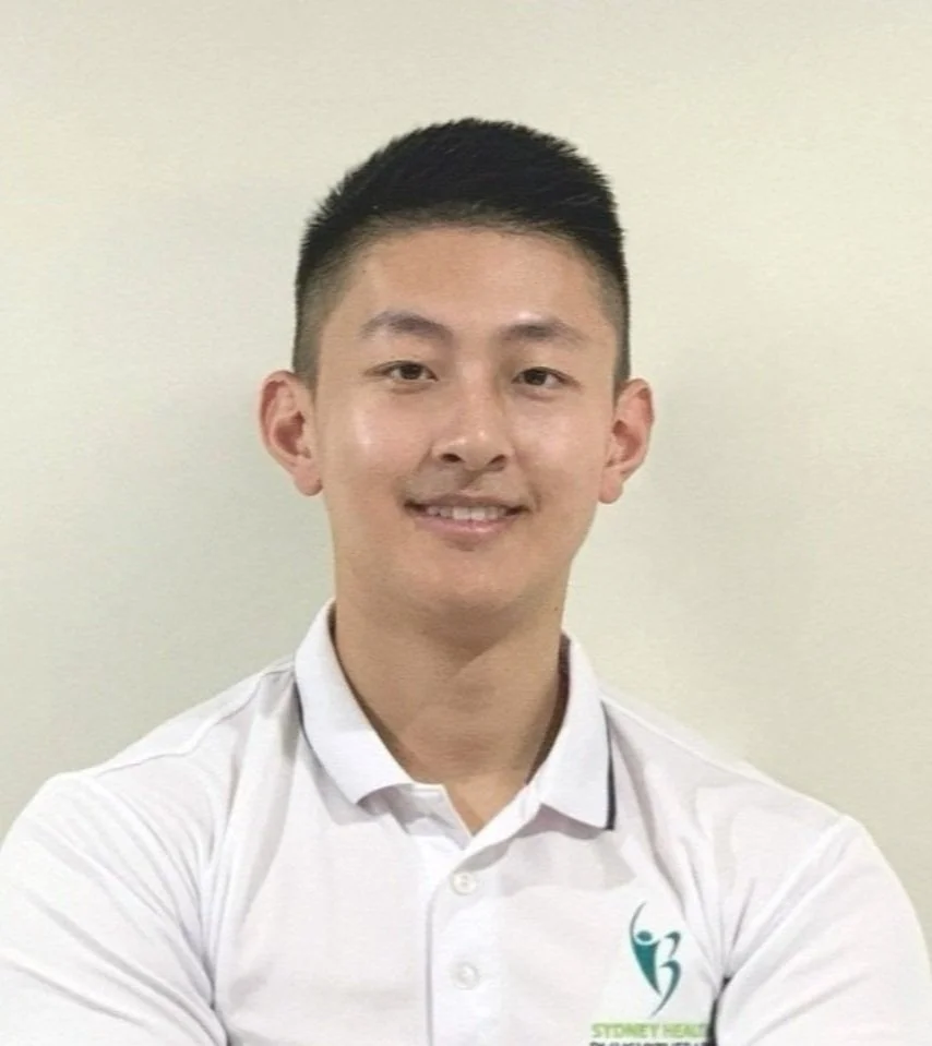 Therapist with faded hair cut wearing white polo and smiling