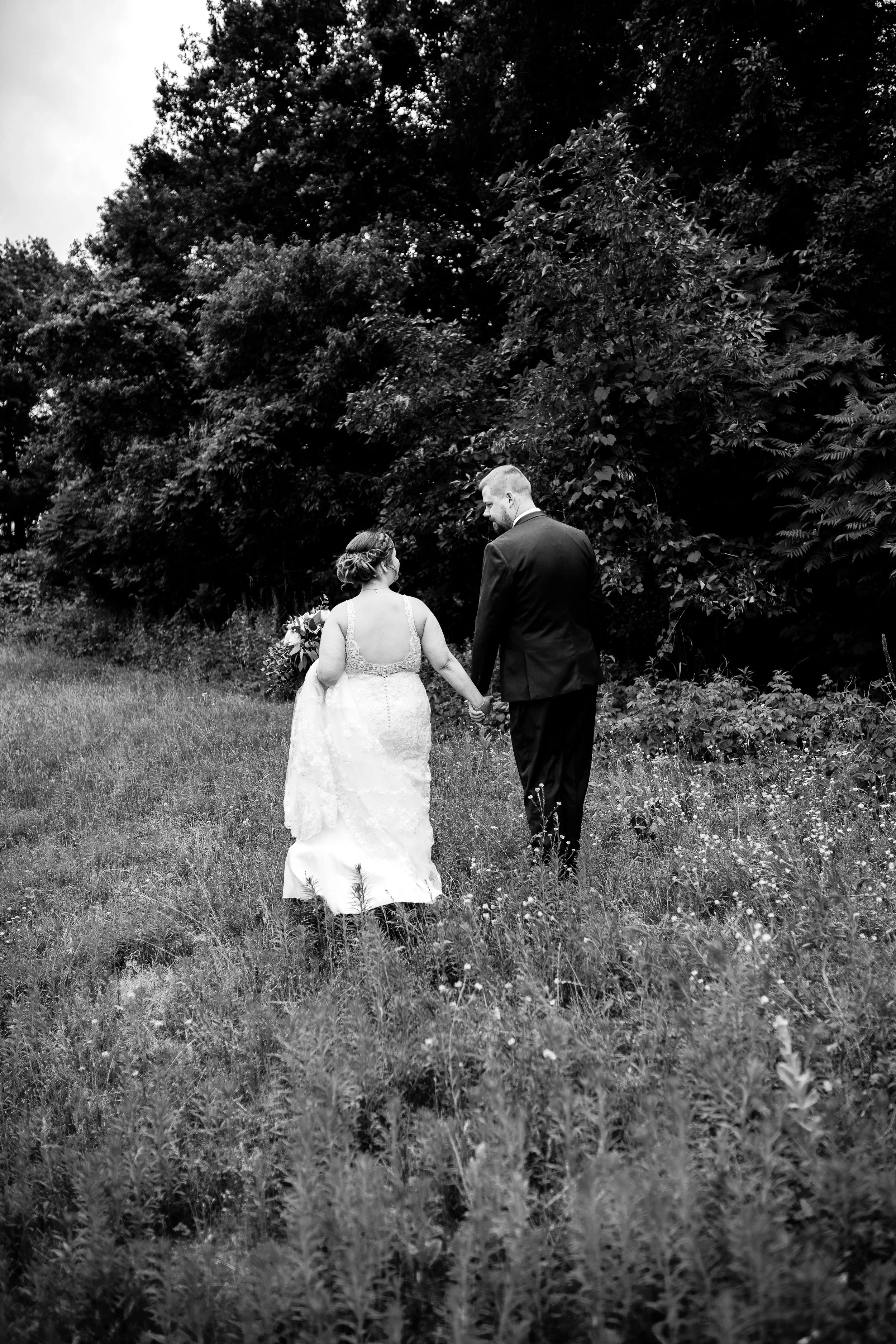 Black and white photo of a couple walking in a field in Minnesota