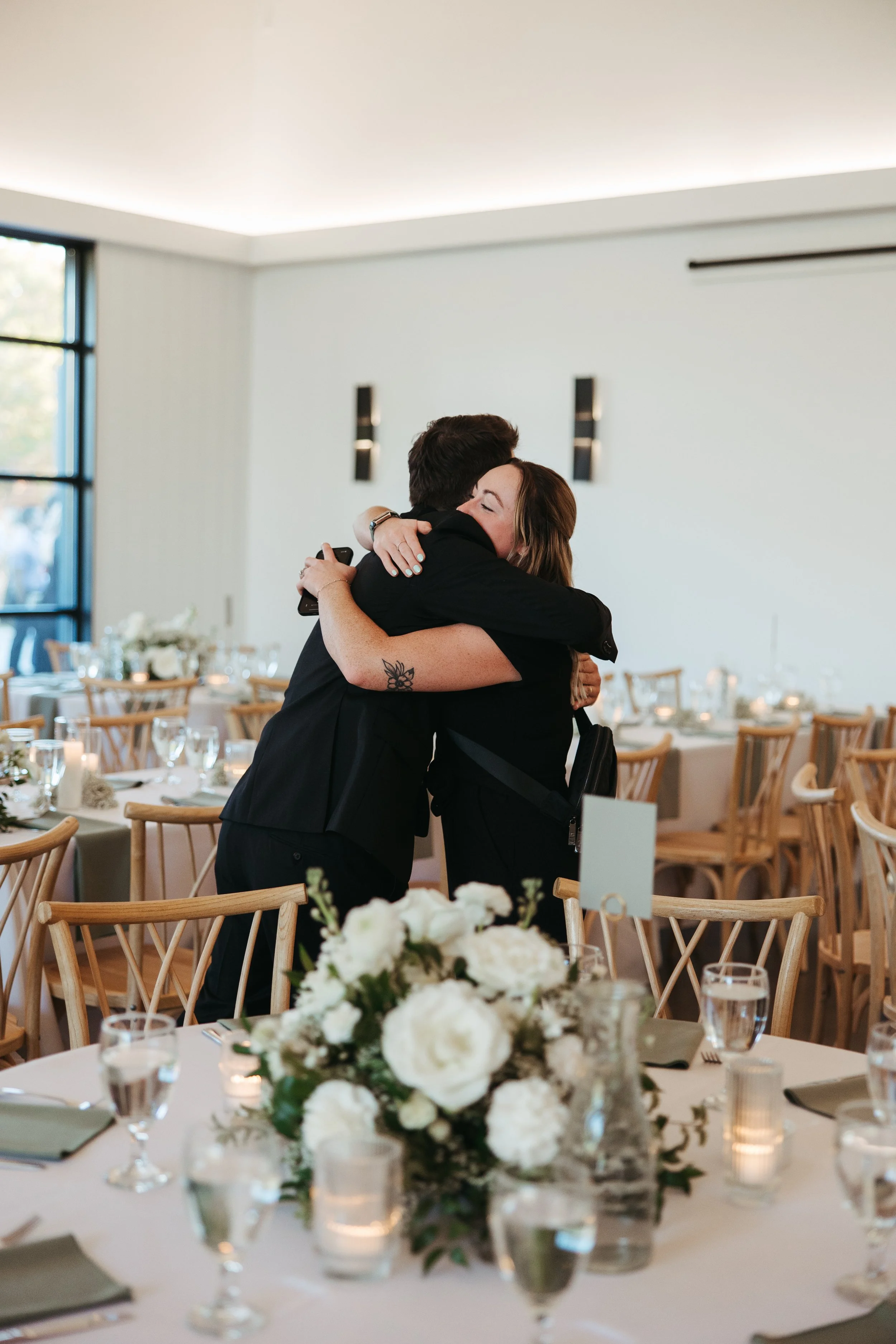 The groom during a room reveal at White & Sable hugging his wedding planner.