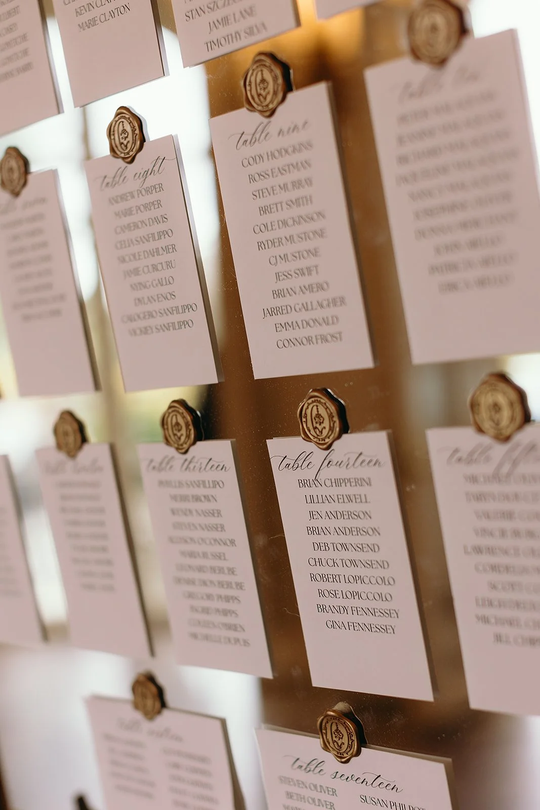 Escort card display at Tupper Manor, with hand calligraphy names and gold wax seals on a mirror 