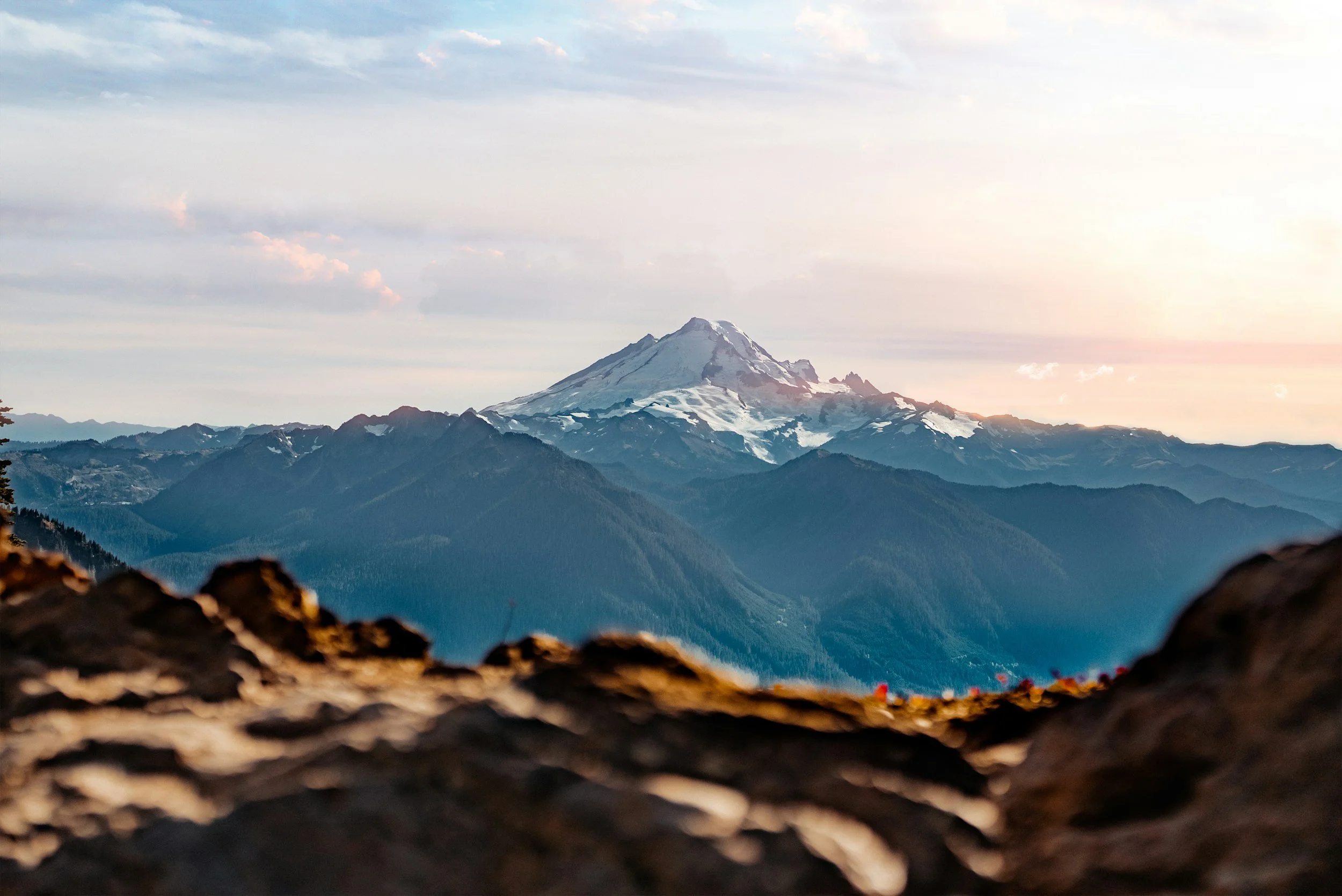 imaoSunset view of snow-capped mountain peak through rocky foreground in the Pacific Northwest - OTW Pacific Northwest trip destination