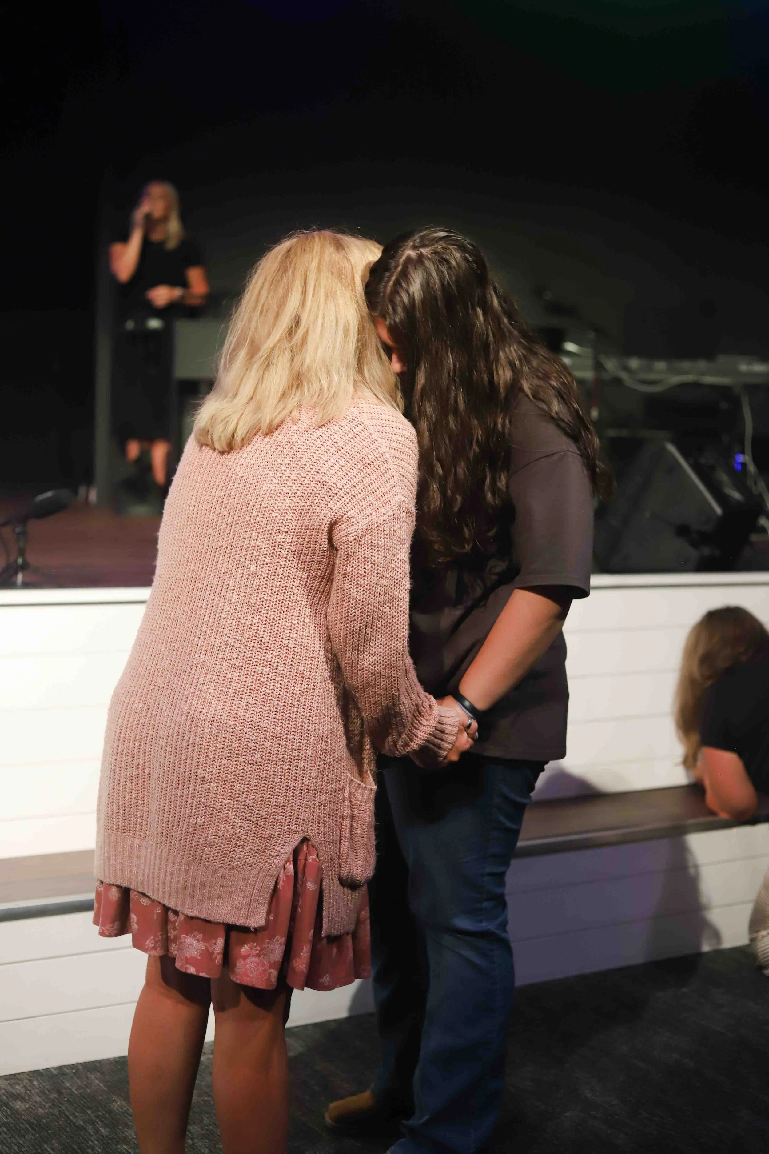 Two women holding hands in prayer at Field of Grace Church in Lebanon Junction, KY