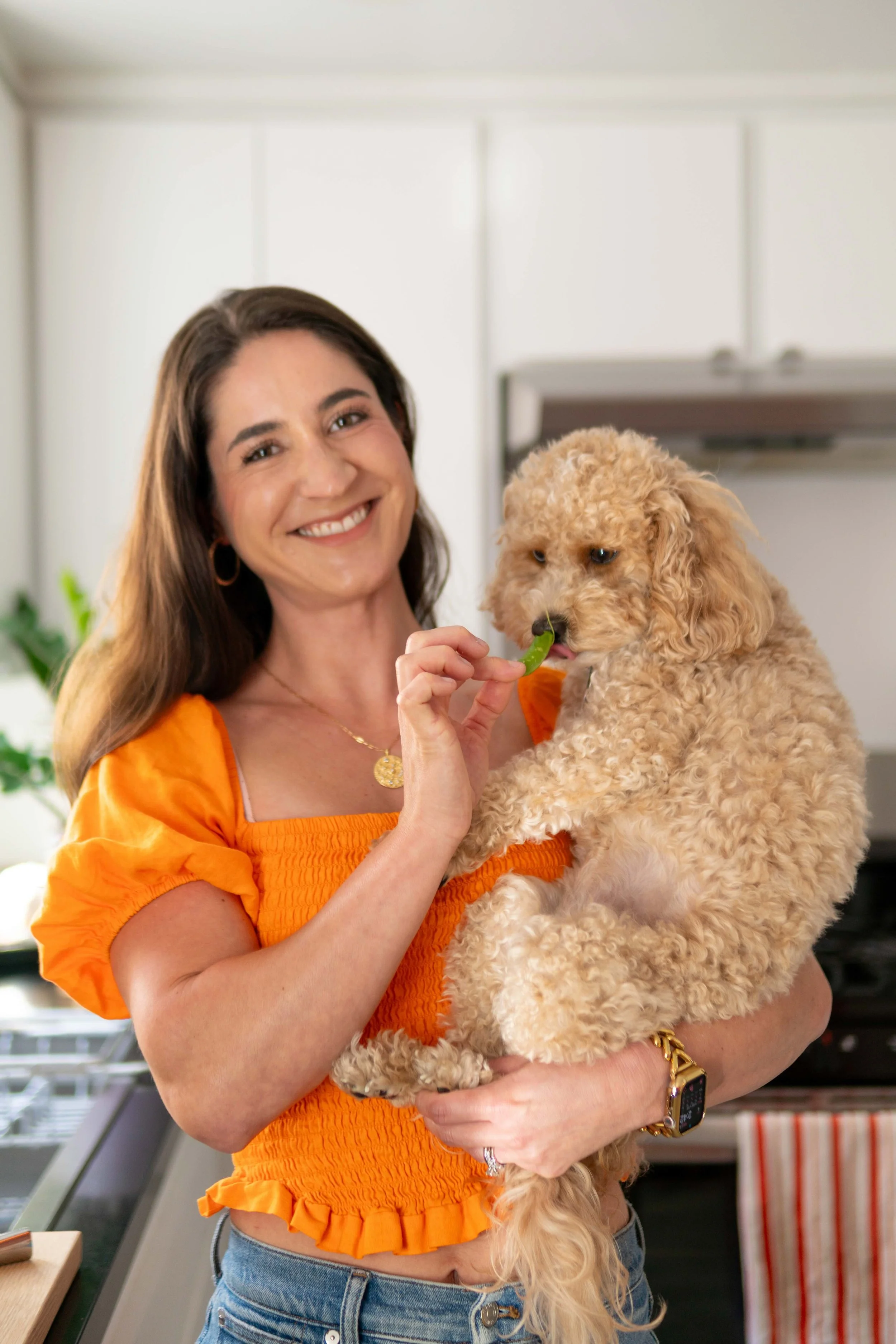 Jillian Beck-Rogers holding her cavapoo dog feeding her a sugar snap pea