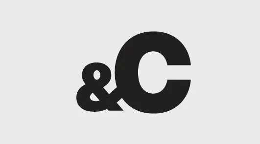 Black ampersand and letter C on a light gray background.