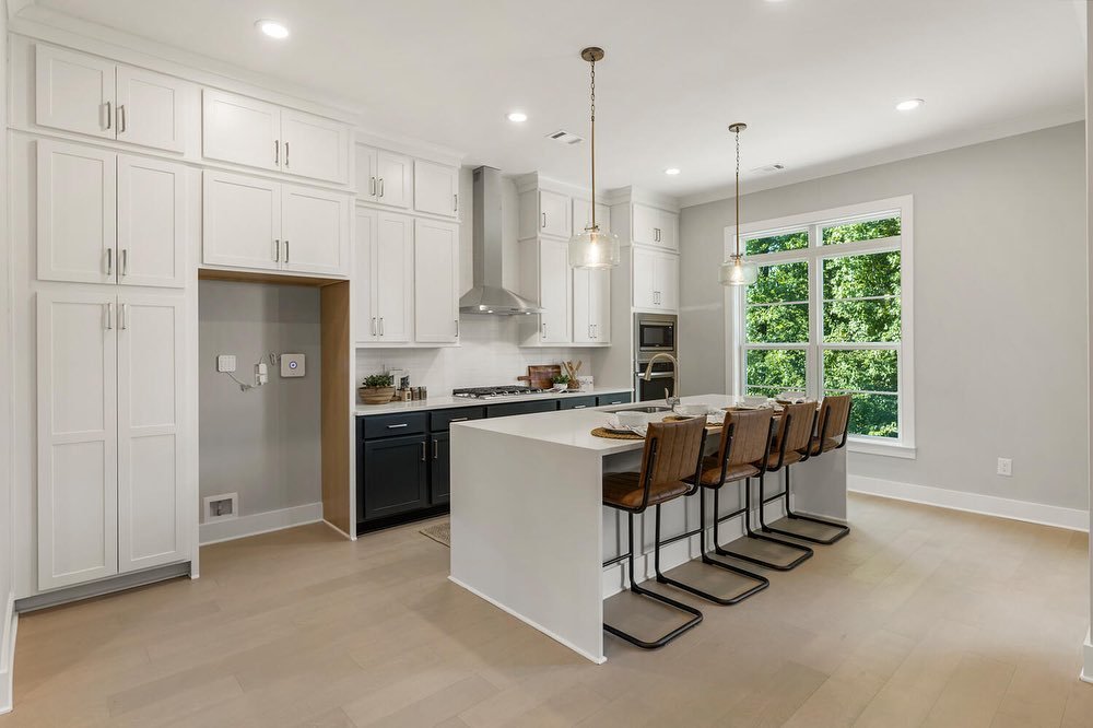 🏡🍽️ Discover the perfect kitchen for your dream home!

Kitchen 1 in Townhome 24 offers a touch of modern elegance with its navy and white two-tone cabinetry, complemented by pale wide plank flooring. The pendant lights with gold detailing add a gla
