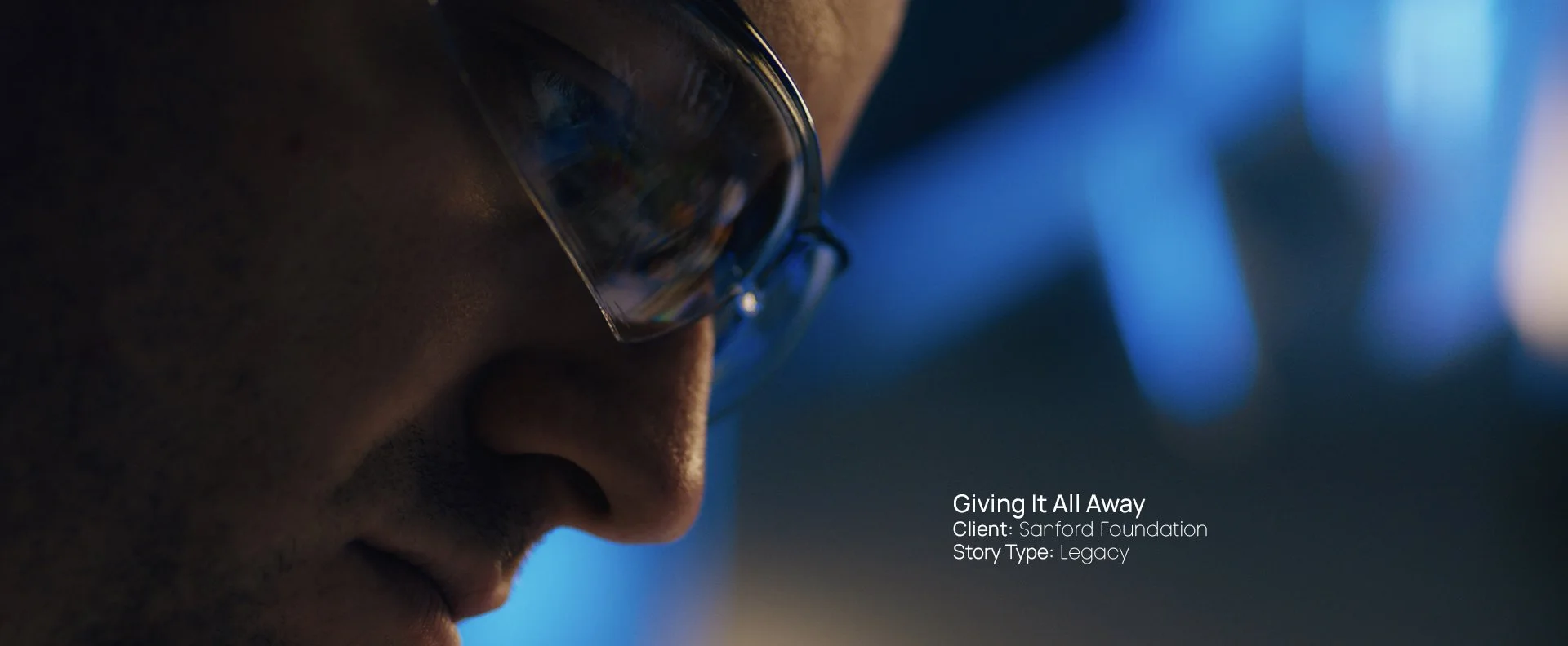 Close-up profile portrait of a medical scientist lit in cool blue tones, still from a Passenger Productions legacy documentary for the Sanford Health Foundation