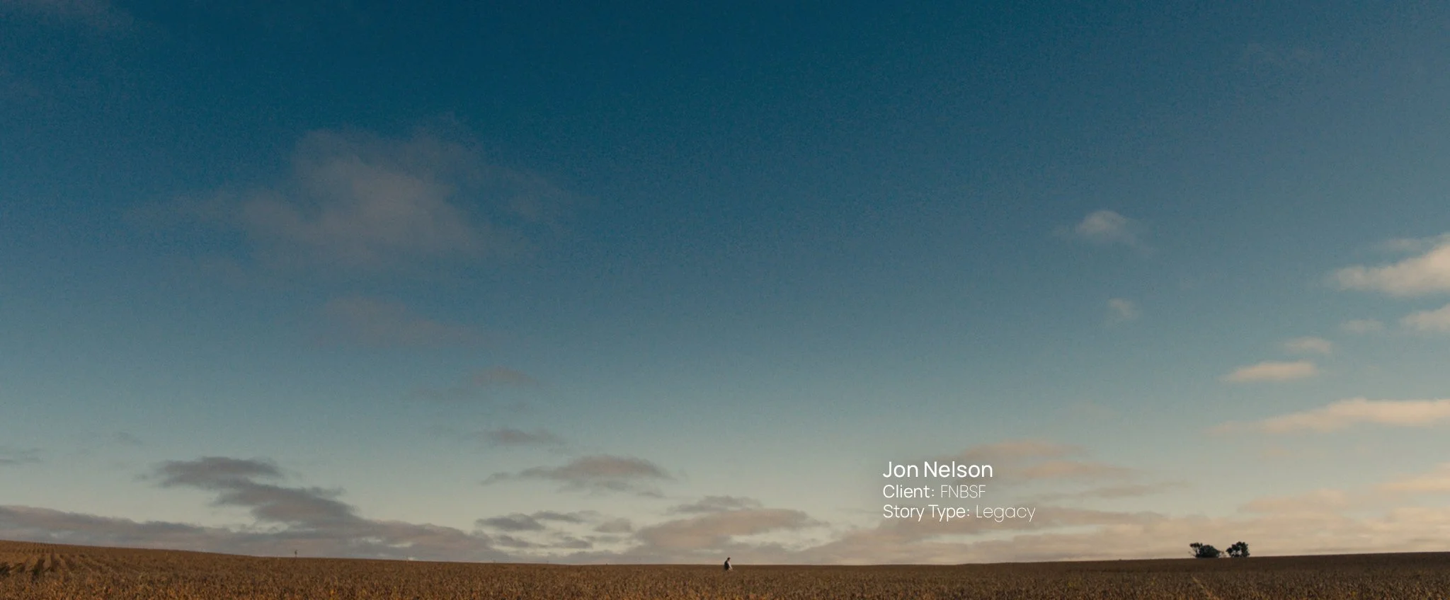 Wide shot of a South Dakota farm field under an open sky at dusk, still from a Passenger Productions legacy documentary about Jon Nelson