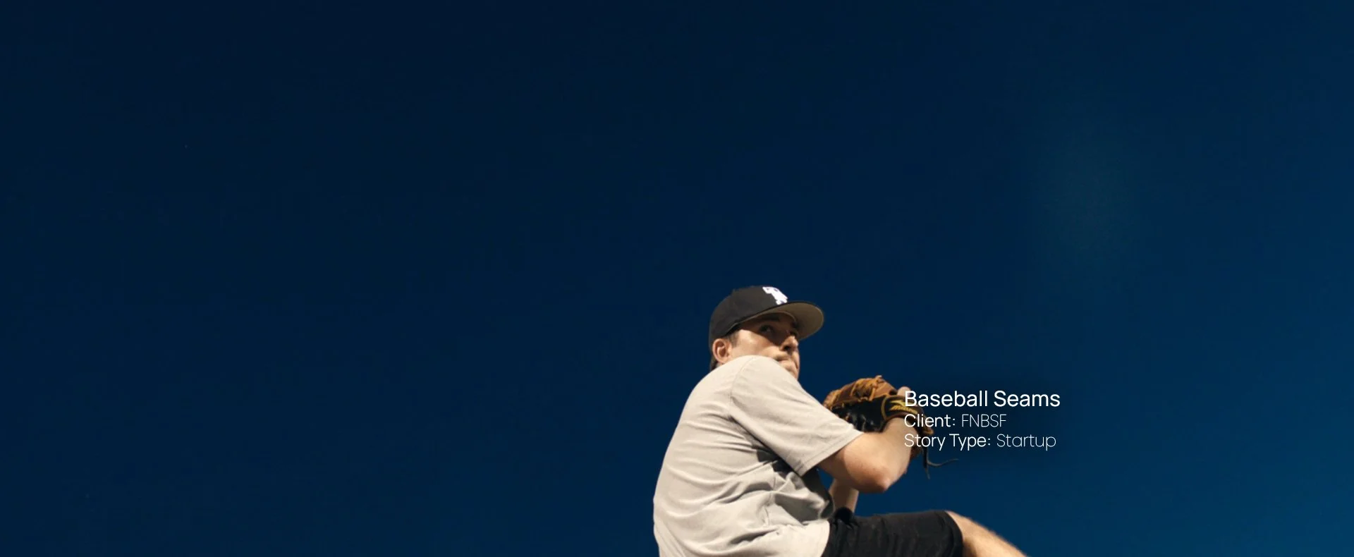 Baseball pitcher mid-windup against a clear blue sky, still from a Passenger Productions startup documentary about Baseball Seams