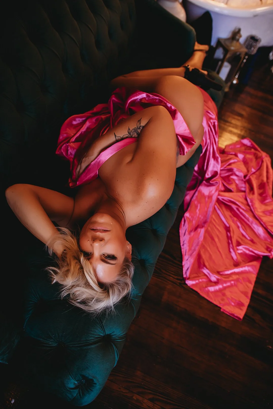 “Implied boudoir pose with moody lighting and a focus on softness, shape, and femininity.”