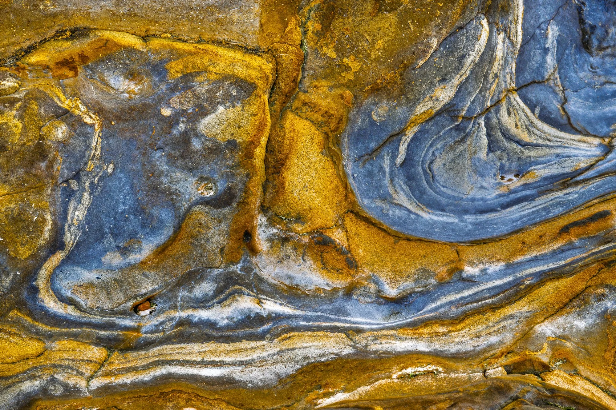 Abstract patterns and swirling colors in rock formations photographed at Weston Beach in Northern California.