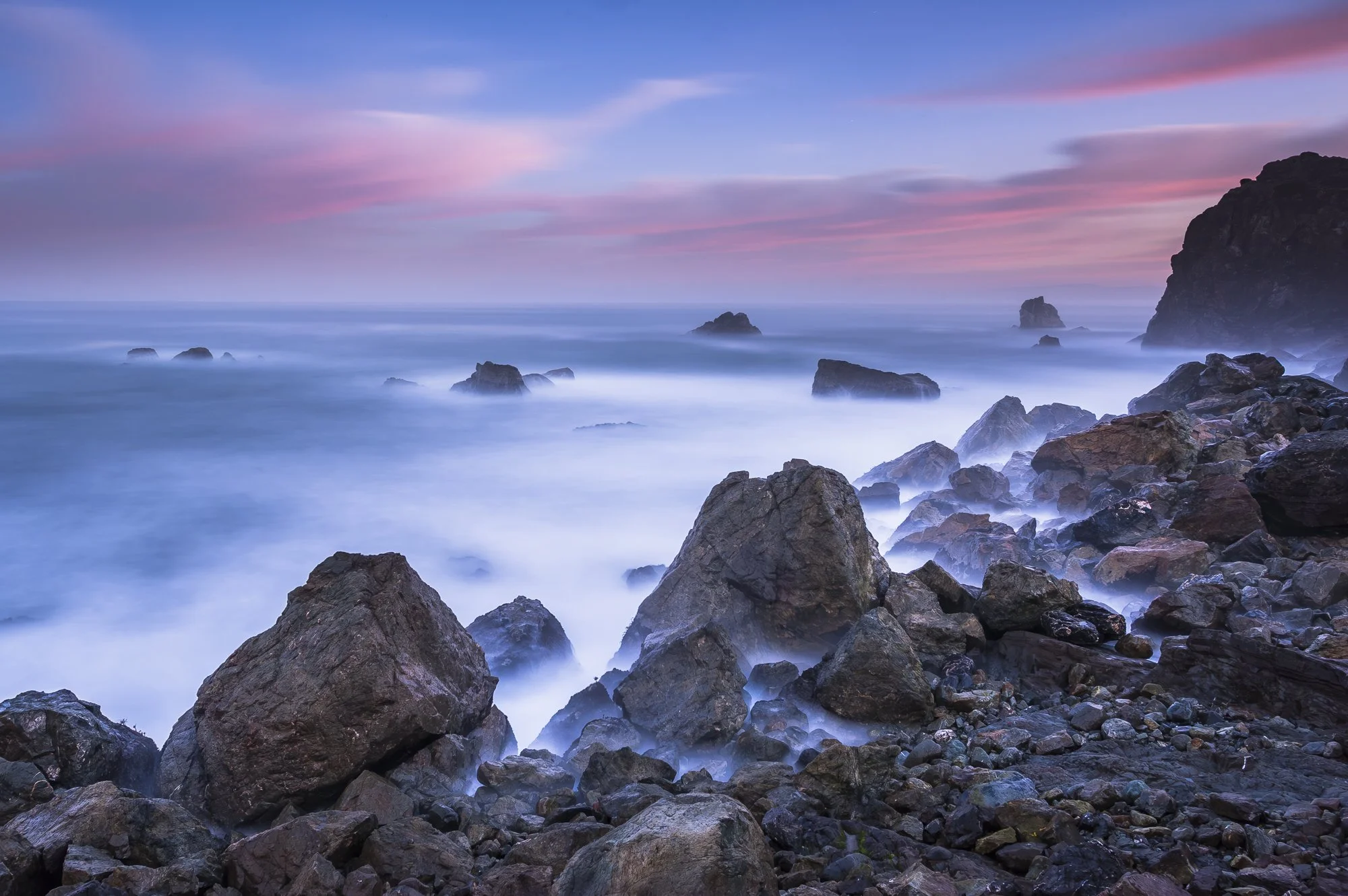Long exposure seascape of rocky shoreline at Patrick's Point in Northern California beneath a colorful sunrise sky.