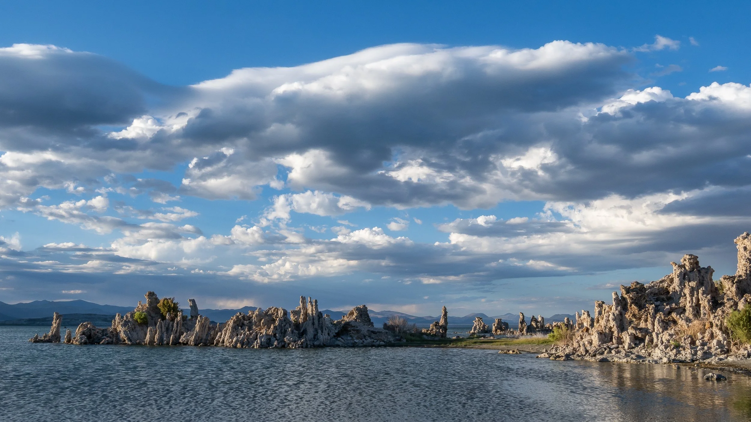 Panoramic landscape of Mono Lake beneath a dramatic cloudy sky, photographed by Joyscapes Imaging.