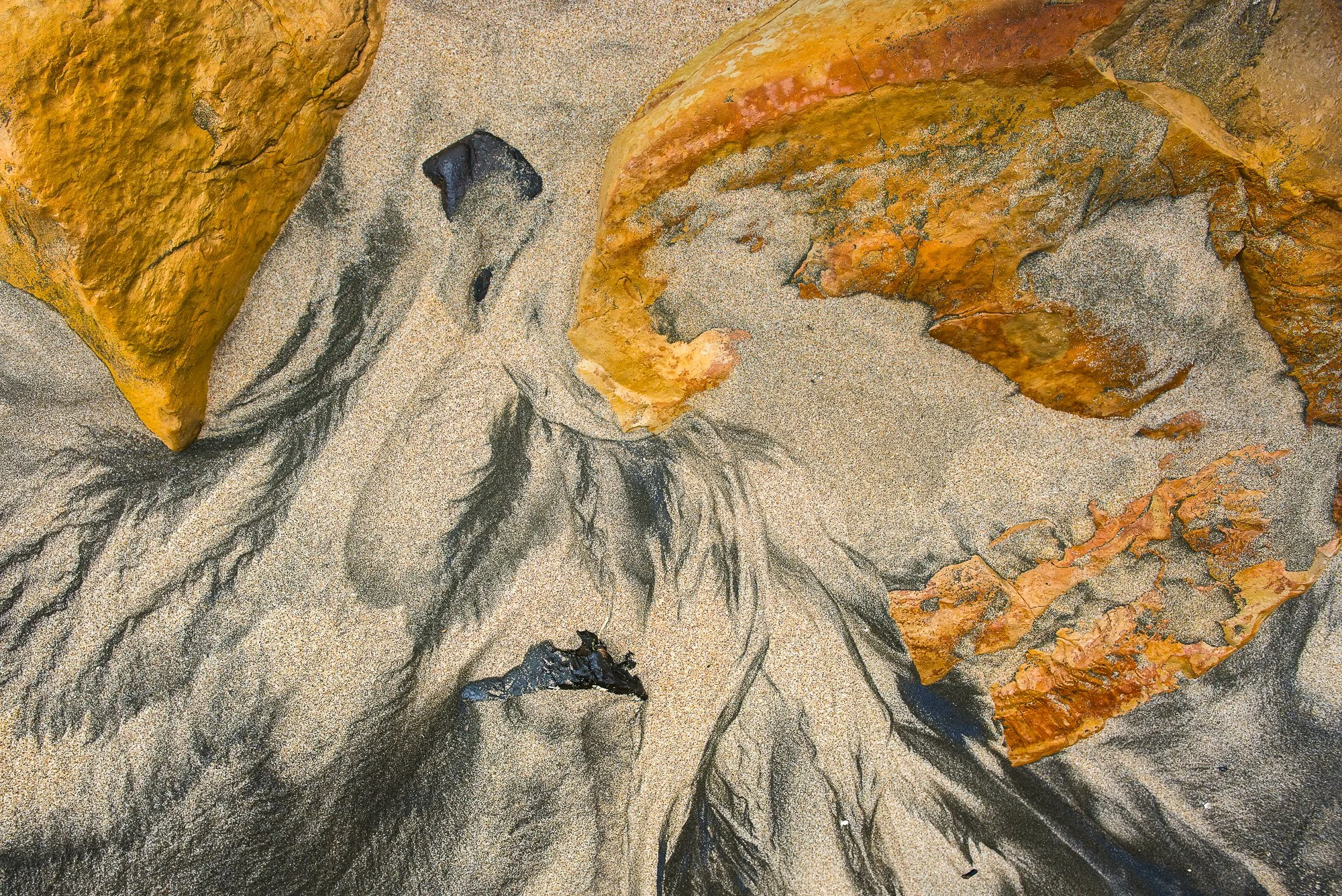 Abstract aerial view of colorful mineral and sand formations shaped by natural processes.