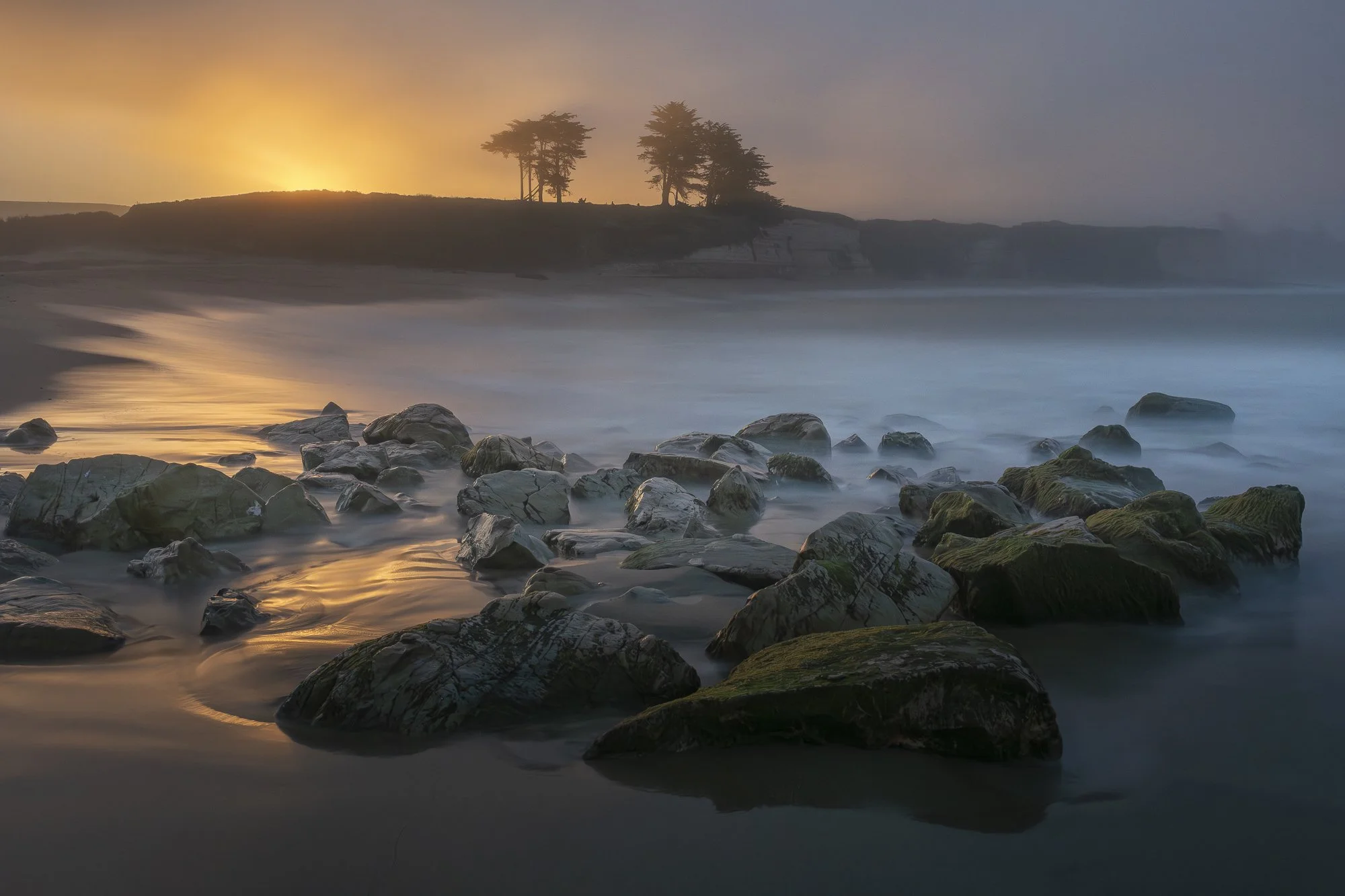 Golden sunrise over the rocky shoreline of Four Mile Beach near Santa Cruz, California.