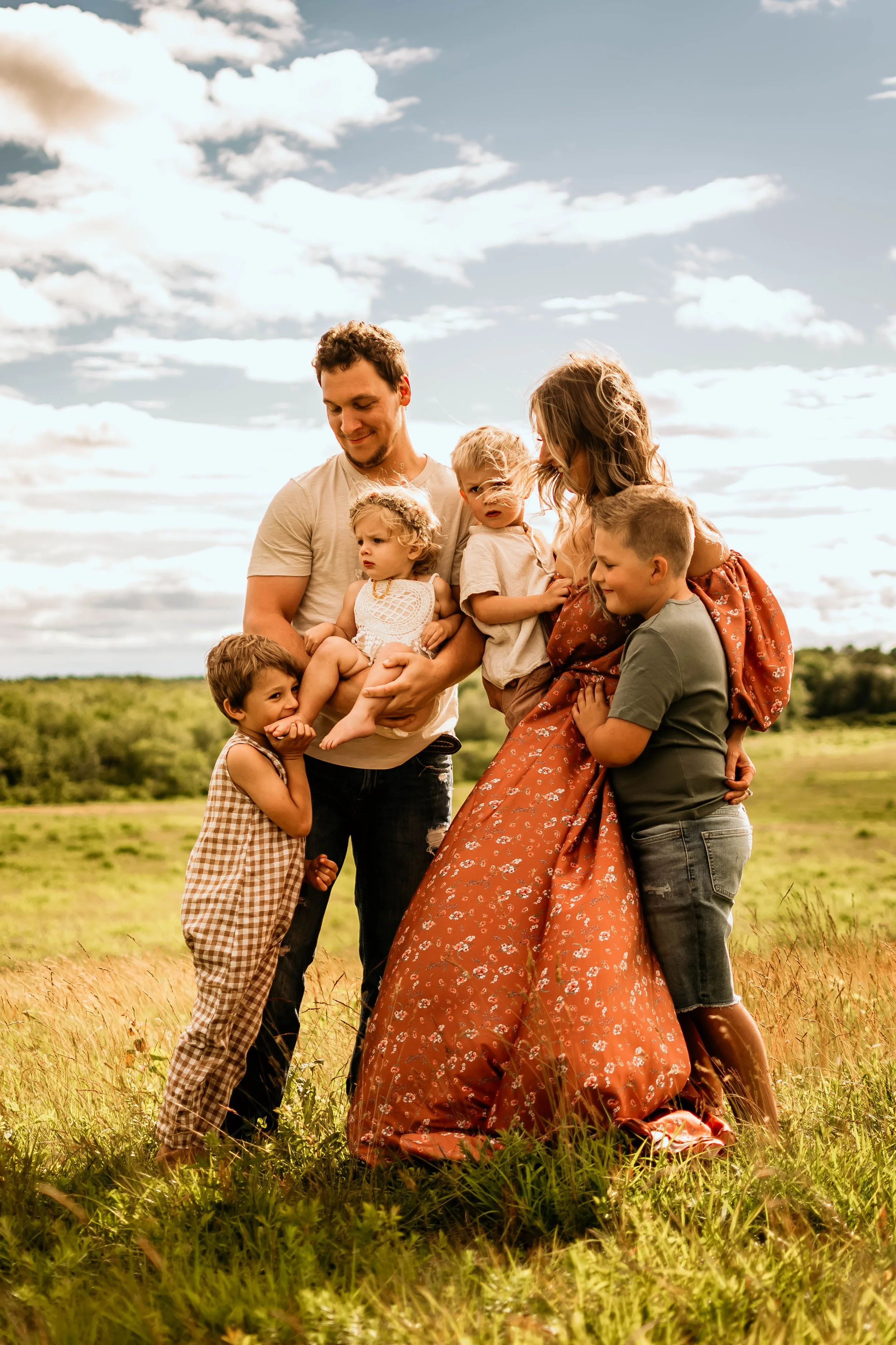 Two sons squish into their Mom and Dad, while holding their other siblings, during a family photoshoot in Wells Maine.