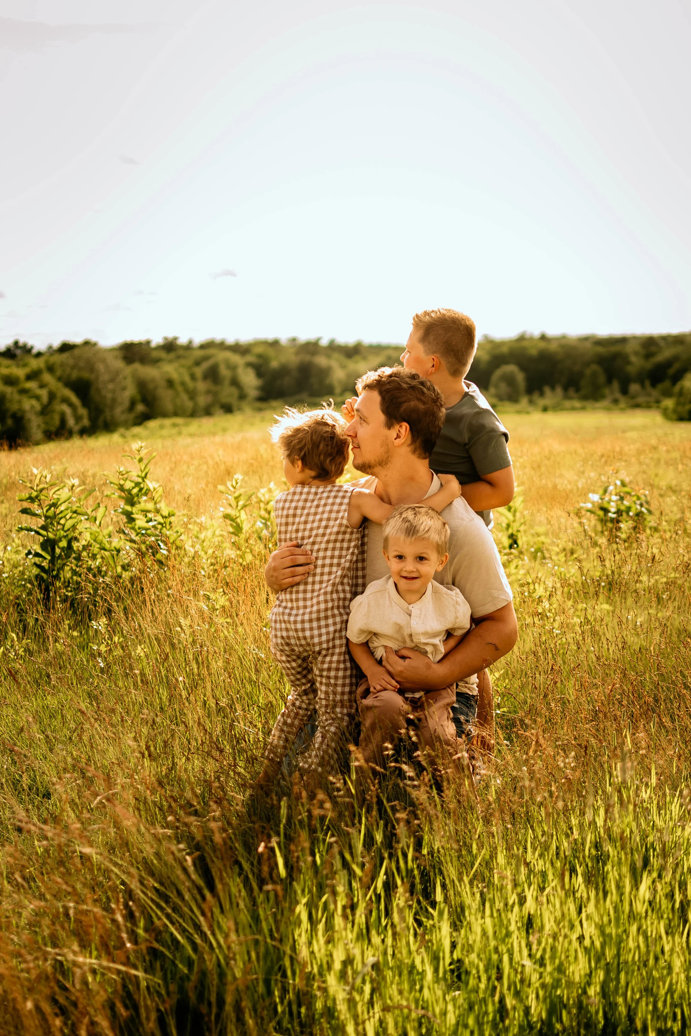 Dad balances all 3 of his boys while playing during a family session in Wells Maine.