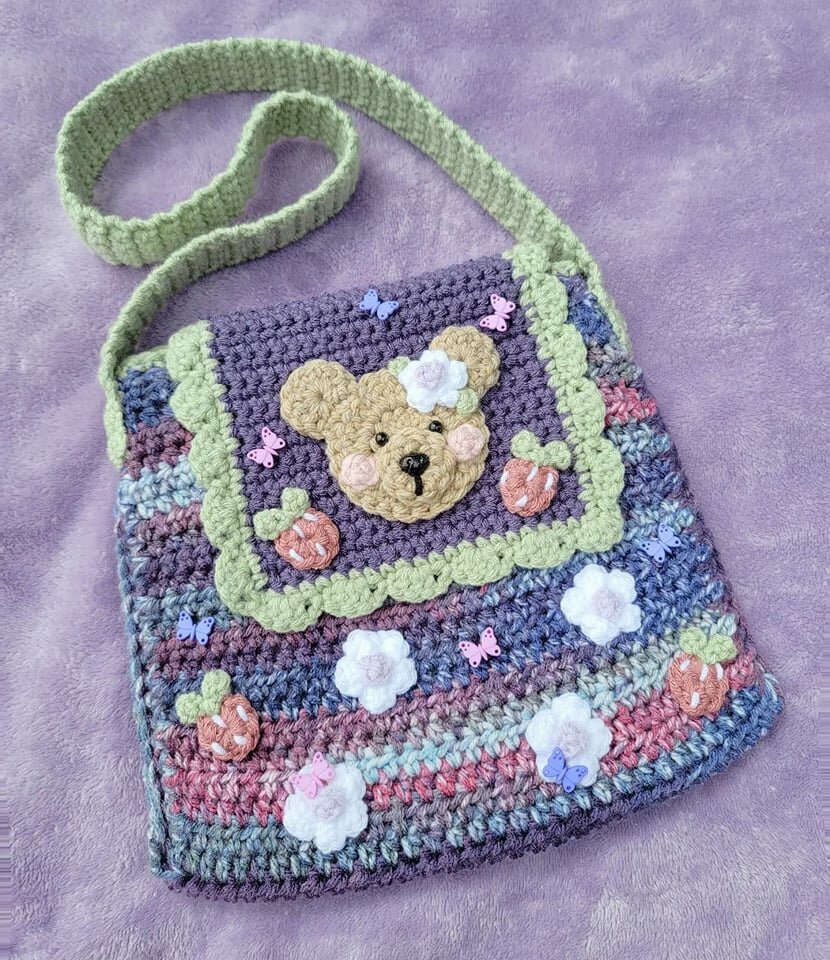 Crocheted handbag with teddy bear face and floral decorations