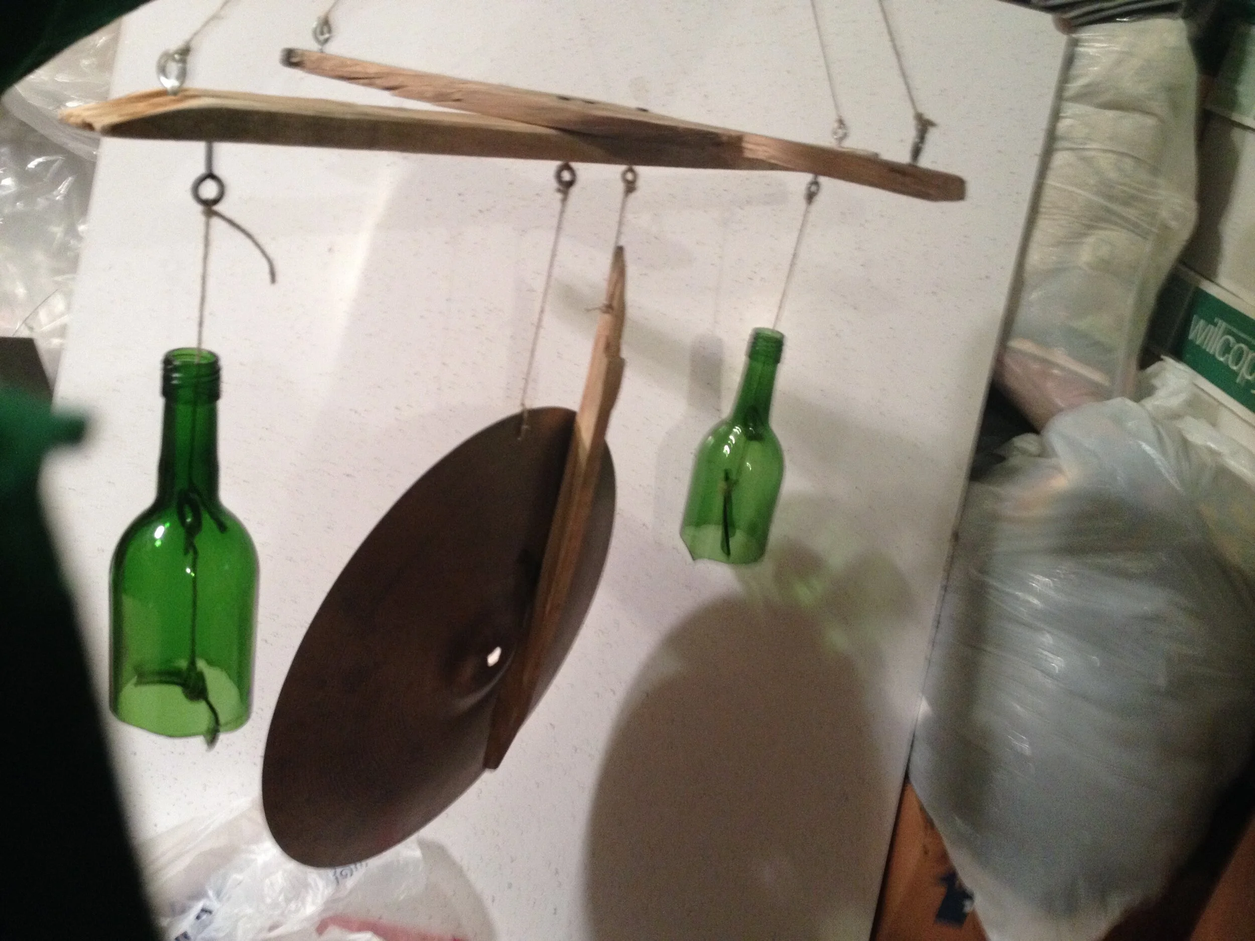 I made a fun little wind chime/mobile art piece for my Mother using recycled wood, cut wine bottles, and an old cymbal. This piece was super fun to design and make. Cutting wine bottles uniformly can be tough! This mobile would catch the wind and you can hear peaceful gong-like sounds from the cymbal, topped with the clinking of the wine glass.