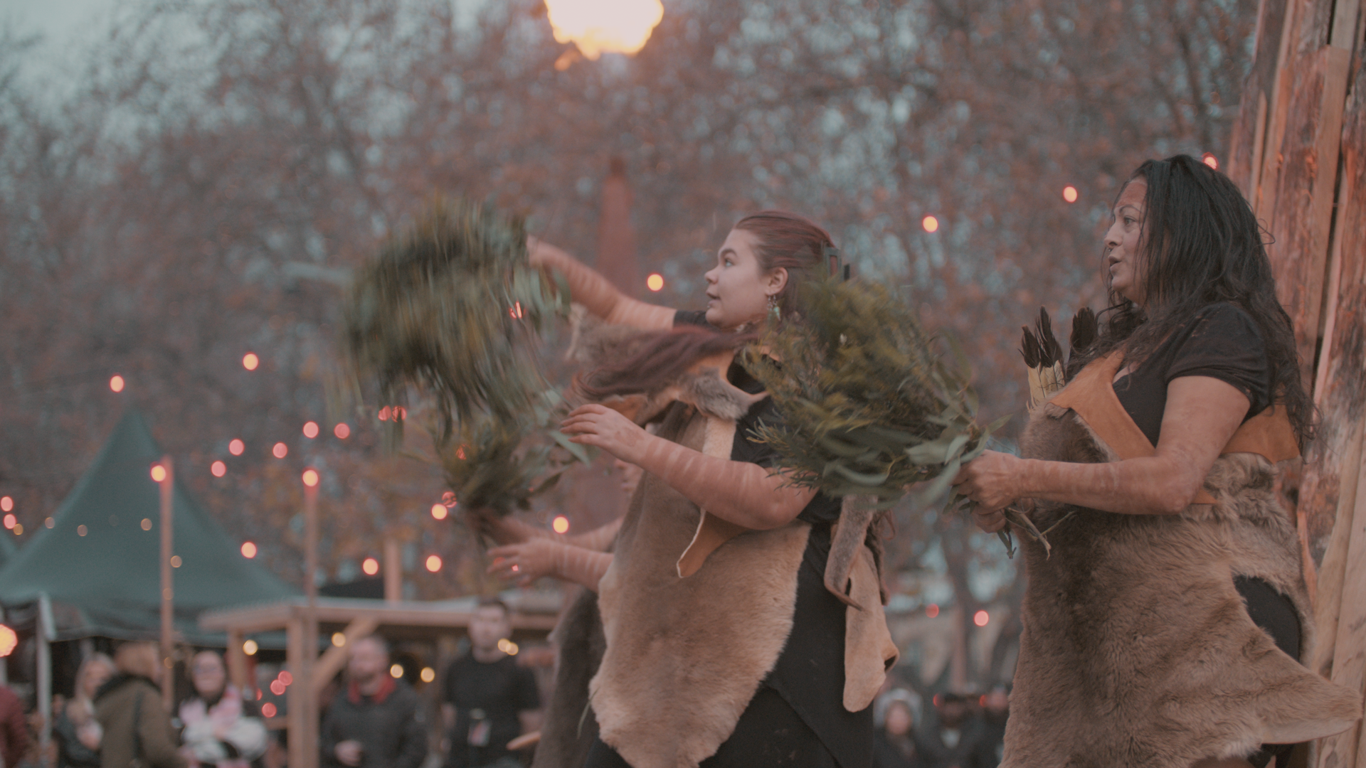 Pakana Kanaplila performers holding leafy branches through smoke during ceremony at The Gathering.