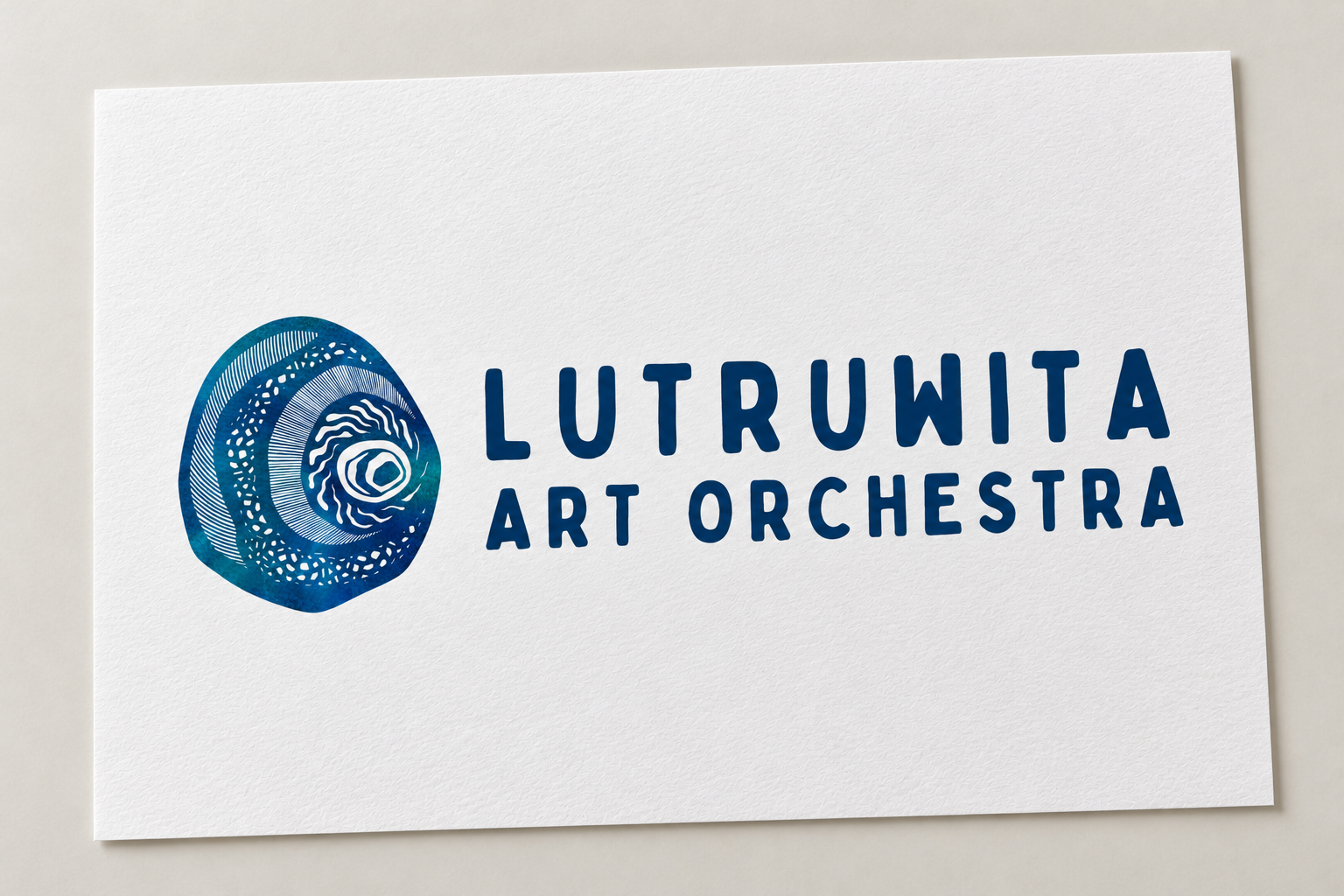 Mock-up of the Lutruwita Art Orchestra logo, pairing blue and teal artwork with navy lettering on textured white paper.