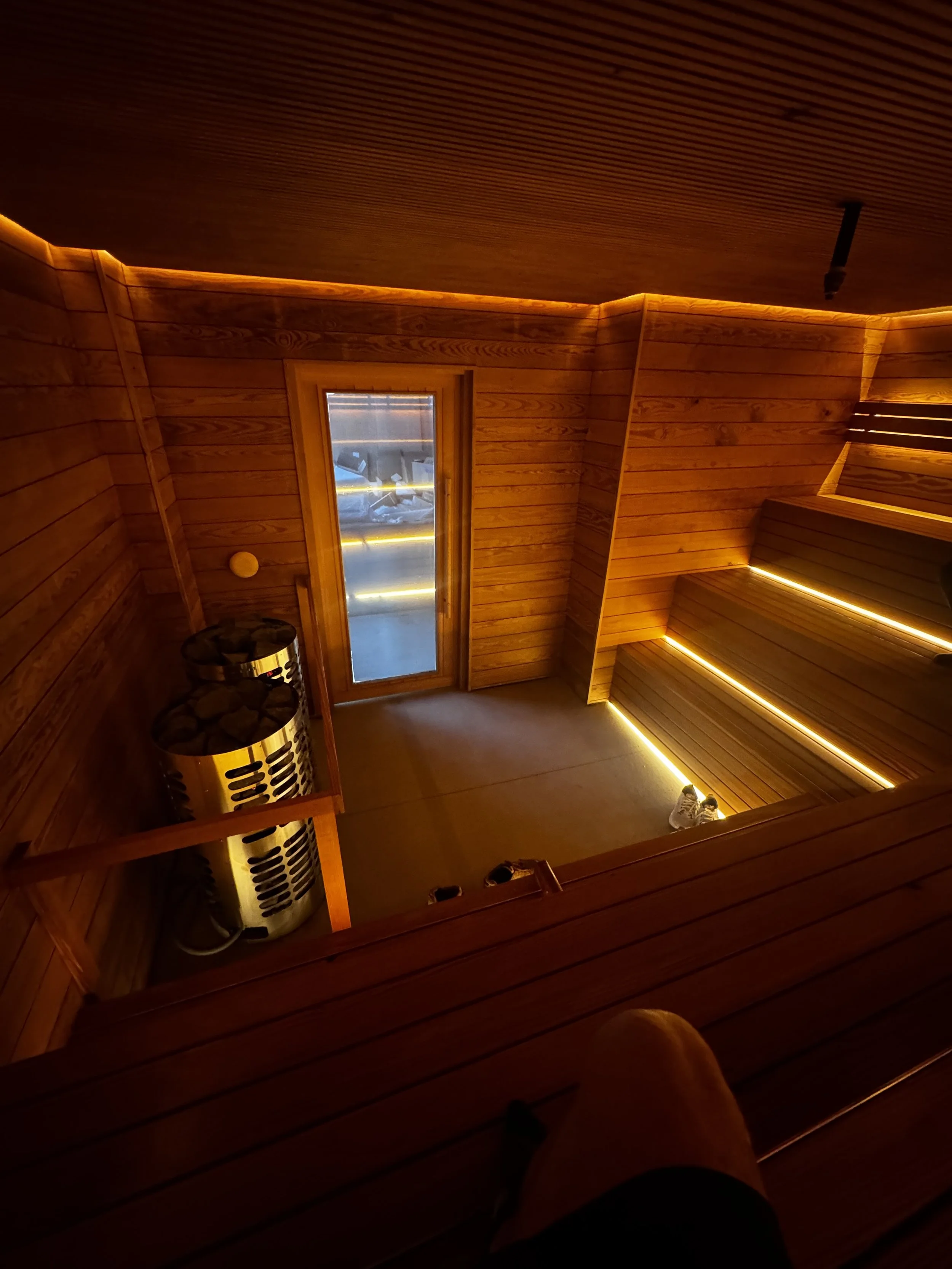 Custom 24 person authentic sauna, three tiers of benches, spacious, cozy, soft warm lighting, soothing experience