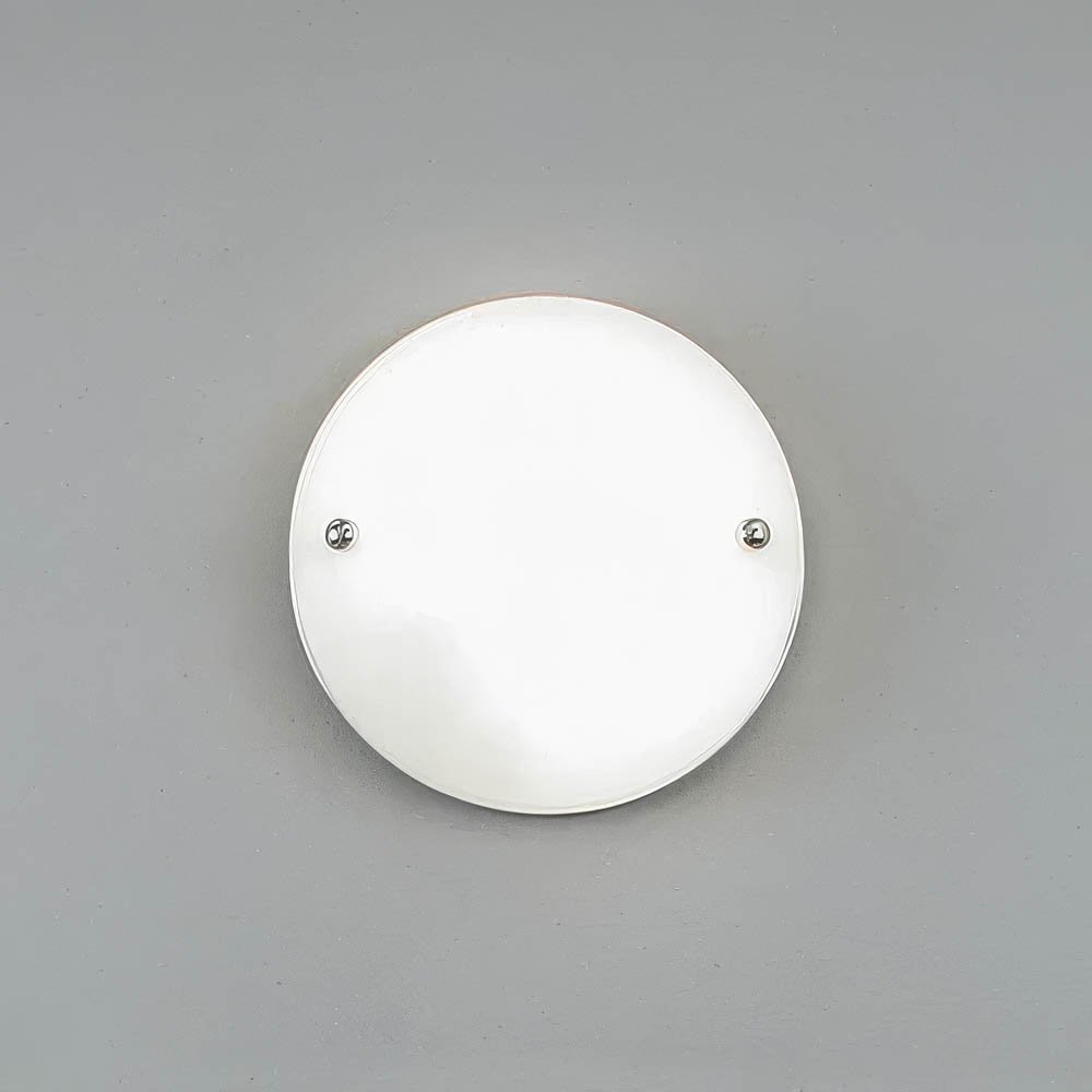 head-on view of circular glass sconce with two polished chrome connector nuts holding glass in place on the wall