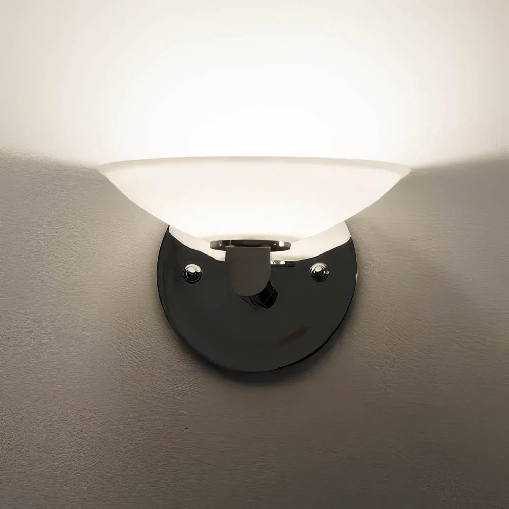 front view of a round glass bowl sconce illuminated on a wall