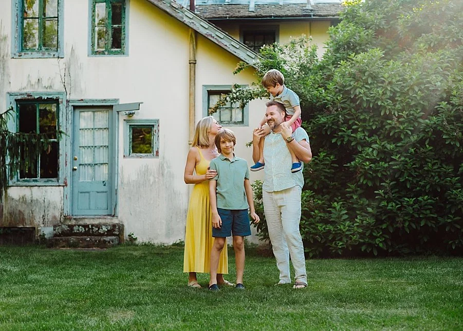 A family of four wearing summer clothes and smiling at each other on green grass