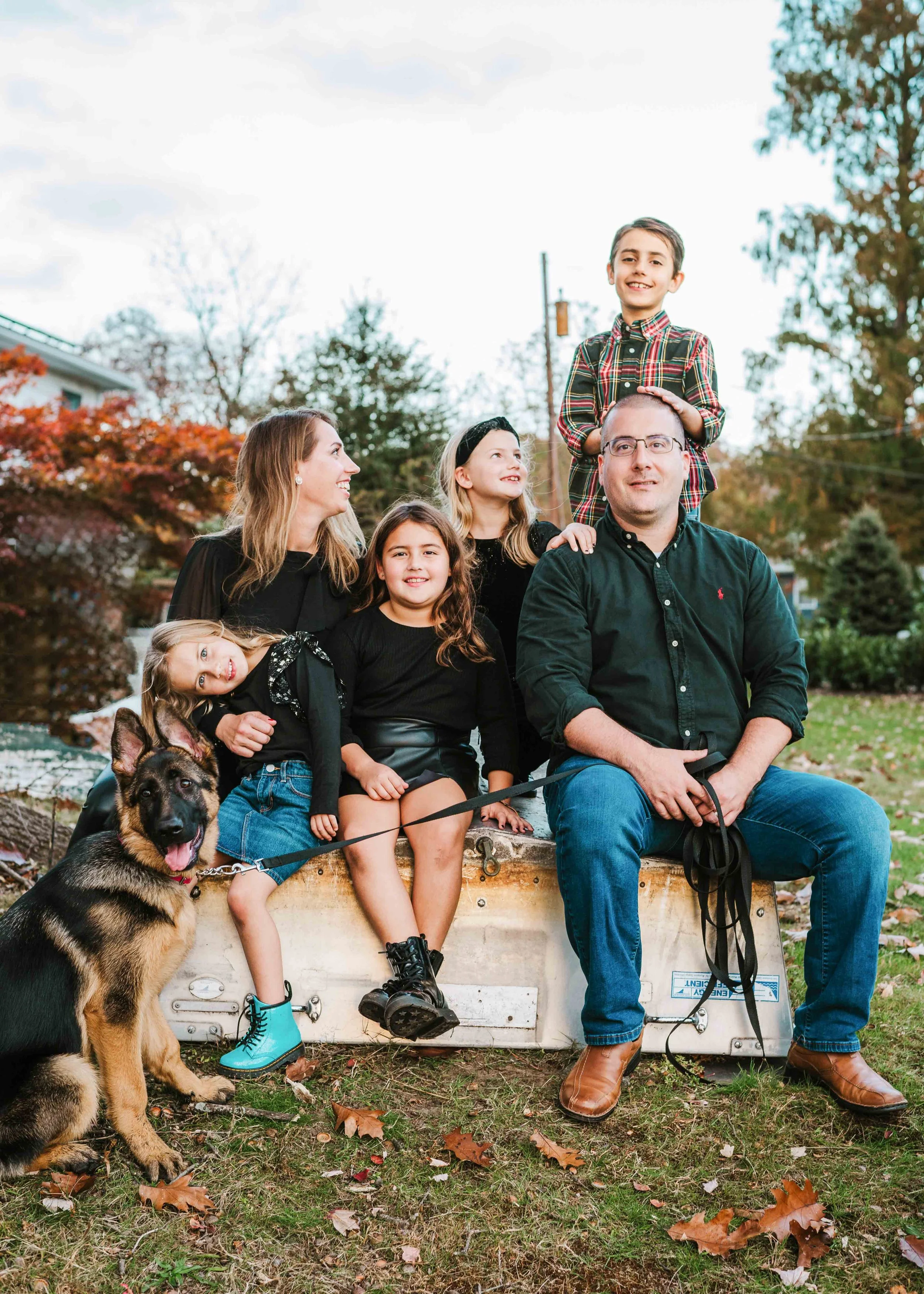 A family of six sitting with a dog and looking relaxed 