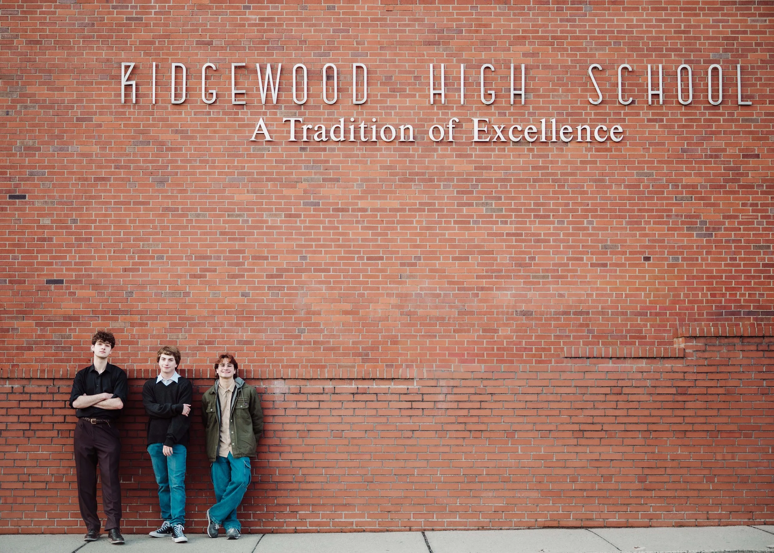 Three boys standing in front of school sign