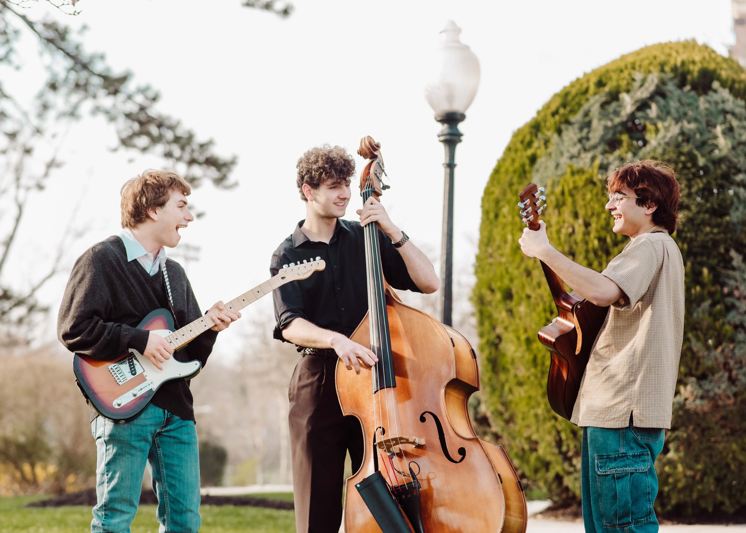 Three boys playing instruments in school grounds