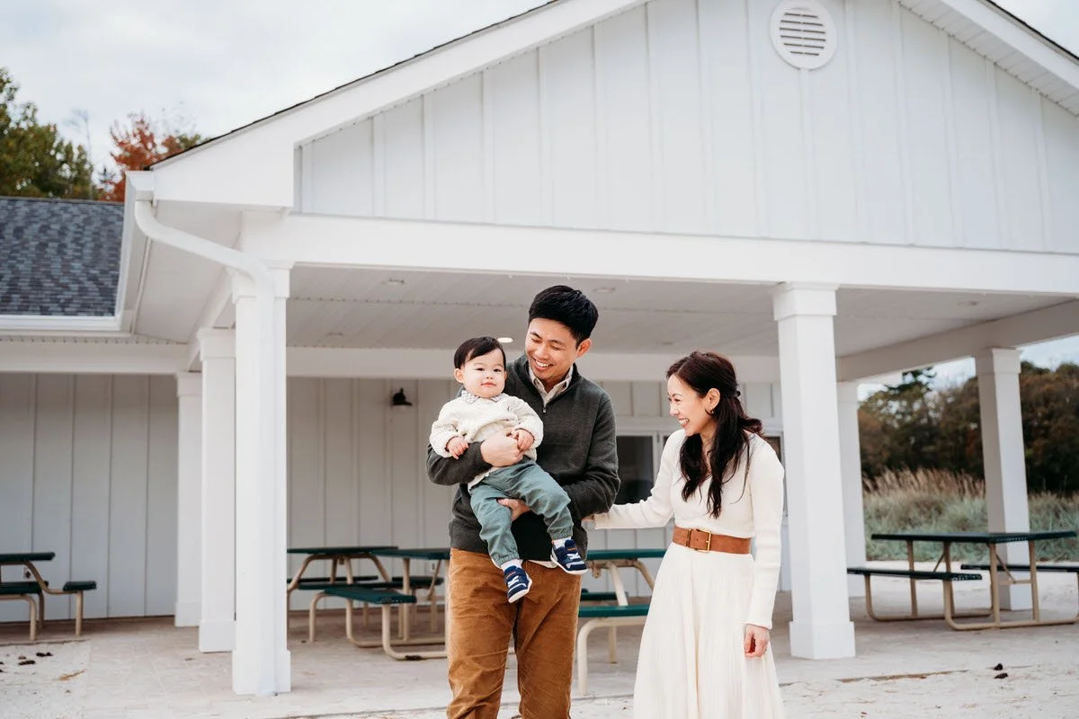 A family of three in front of a white structure smiling 