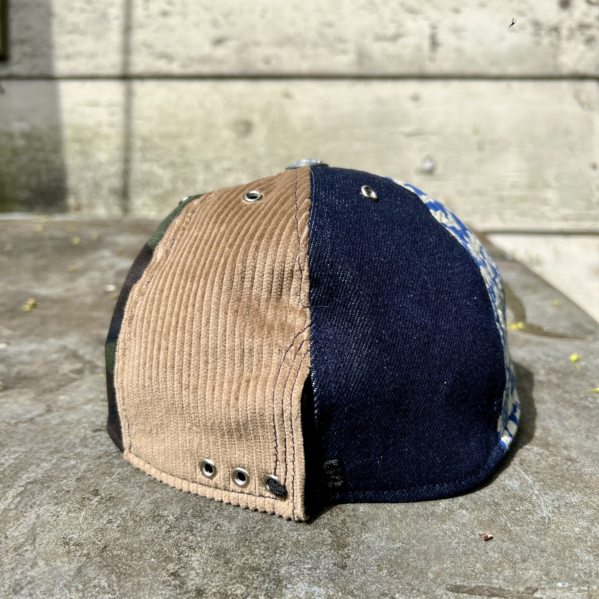 Back view of dark mixed-panel cotton cap with beige corduroy, deep navy and blue-and-white quilted cotton panels.