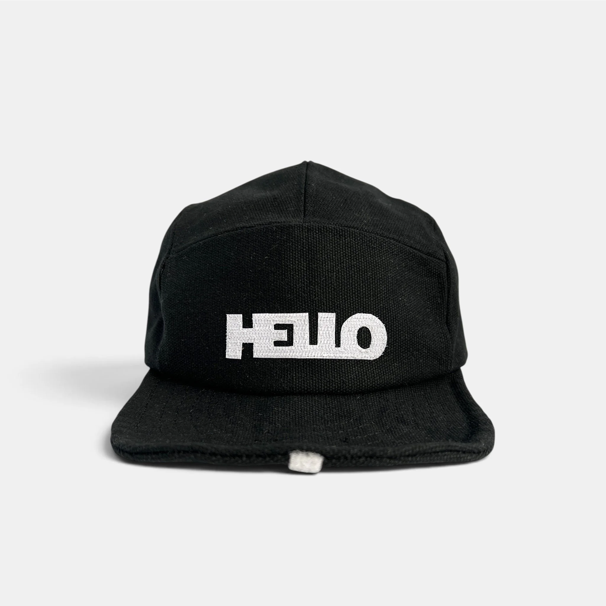 Front view of black canvas five-panel cap with white HELLO greeting motif and roll-up visor.