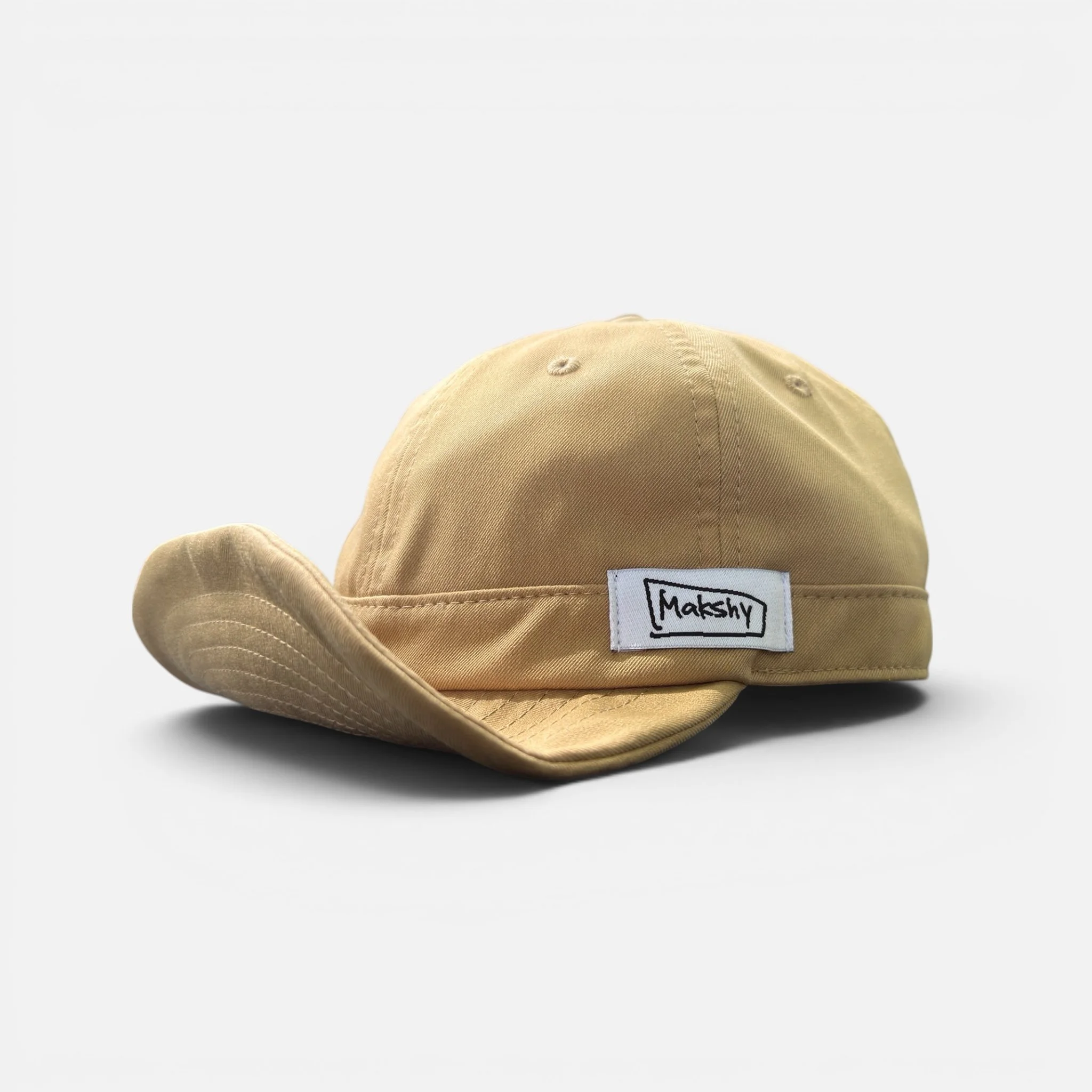Beige six-panel baseball cap in Japanese technical fabric with shapeable wired visor and foldable design.