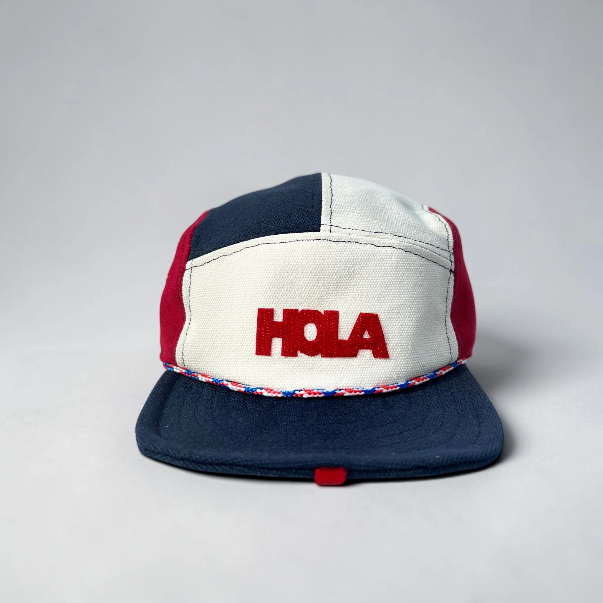 Red, white and navy 5-panel baseball cap with red HOLA velcro motif and navy roll-up visor.