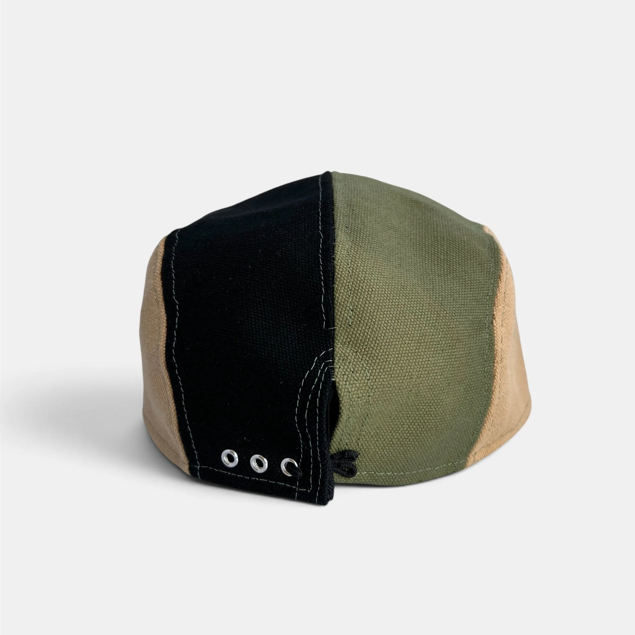 Back view of olive, black and beige cotton canvas five-panel cap with adjustable closure and metal eyelets.