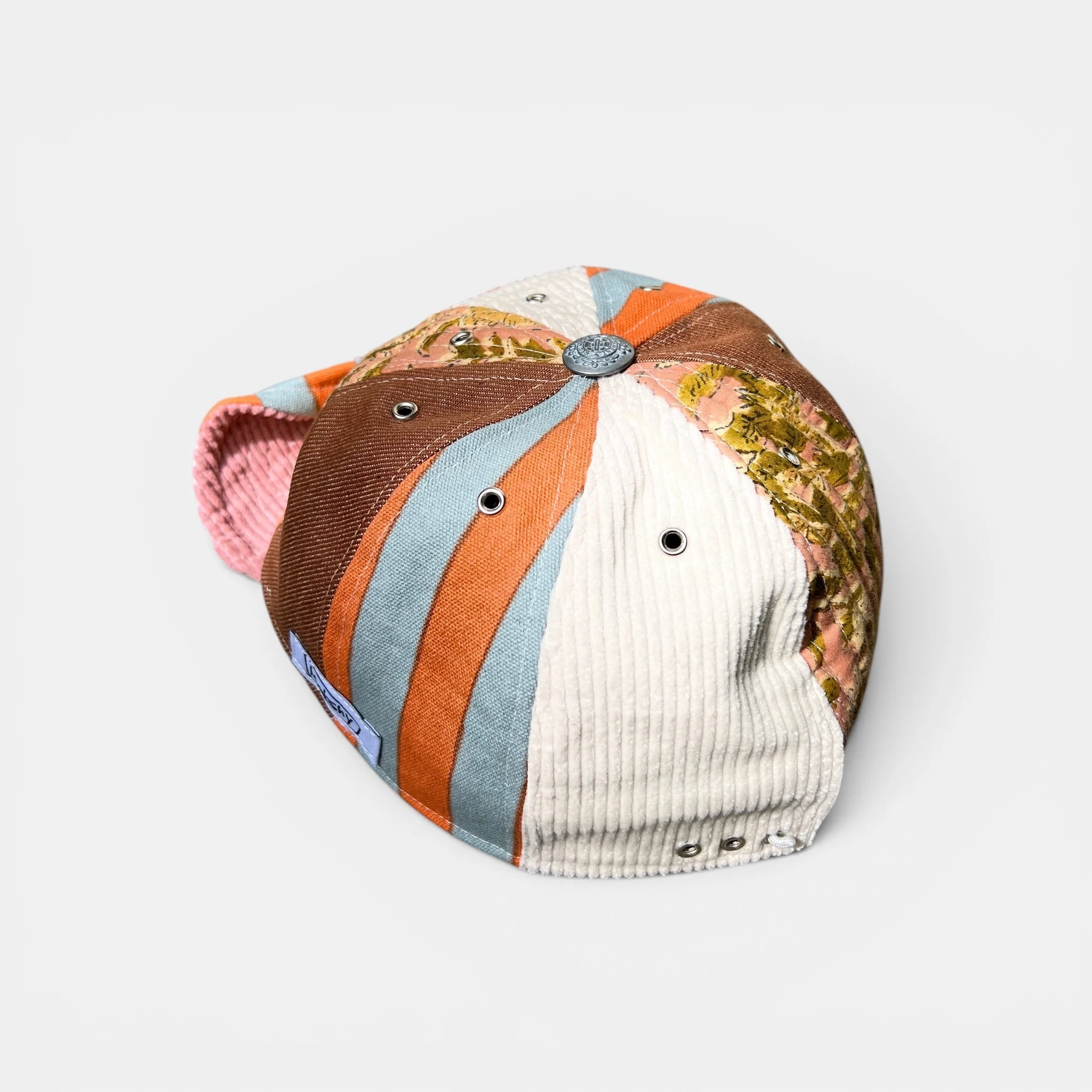 Mixed-panel cotton cap in light tones with corduroy, striped and botanical-print panels, shown from the back.