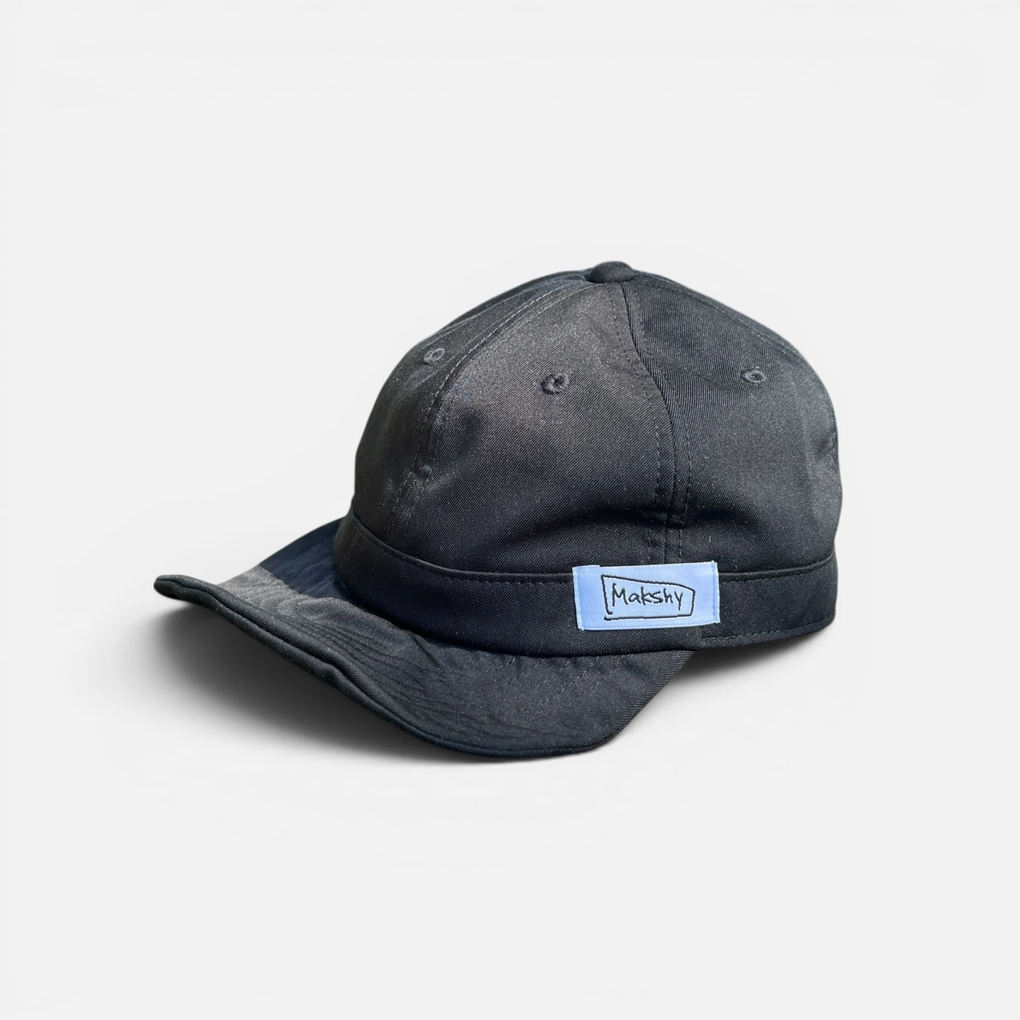 Black six-panel baseball cap in Japanese technical fabric with shapeable wired visor and foldable design.