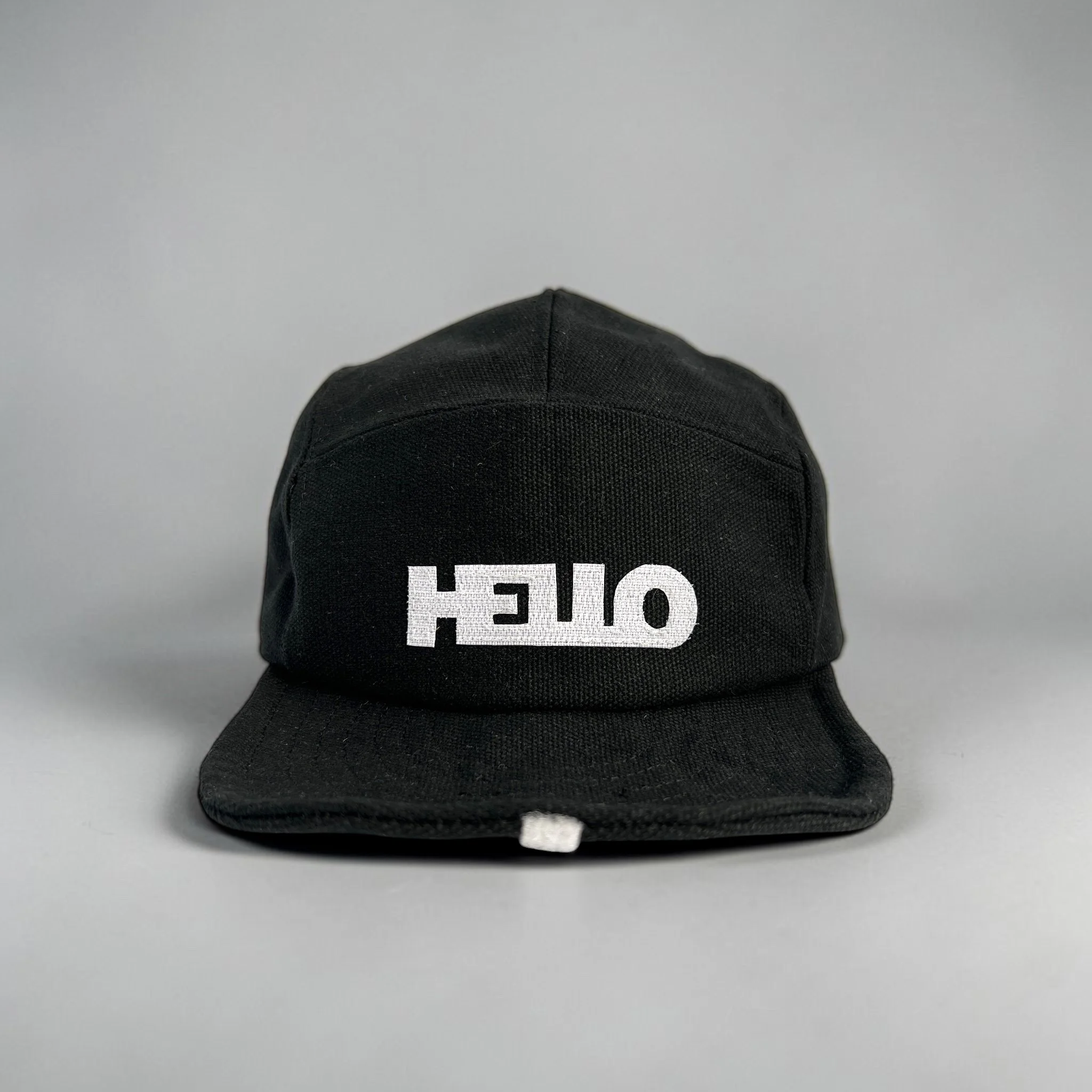 Black cap with white block letters spelling 'OFFICE' on the front, placed on a gray surface.