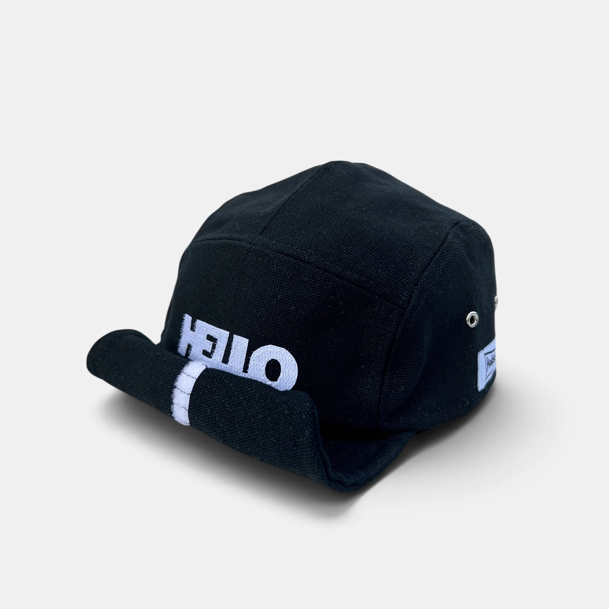 Black cotton canvas five-panel cap with white HELLO greeting motif and roll-up wired visor.