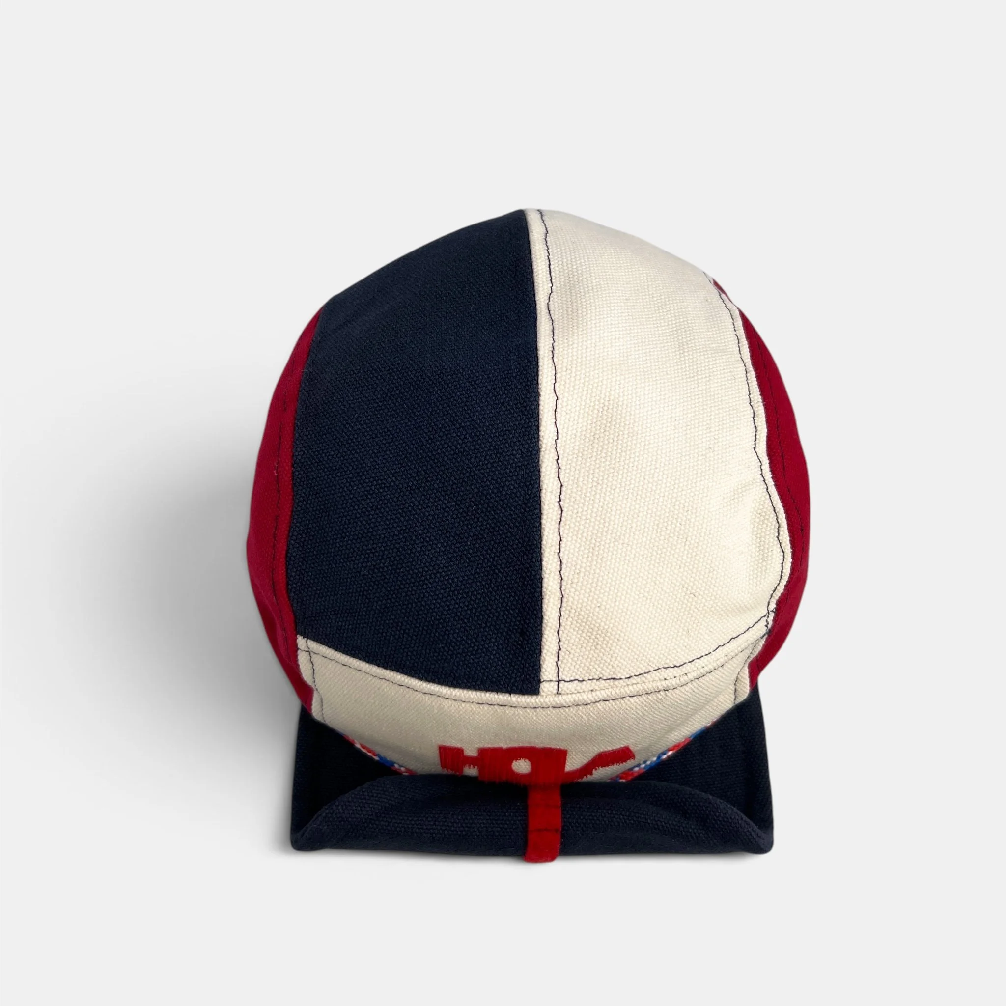 Top view of red, navy and off-white cotton canvas five-panel cap with colour-blocked panels.