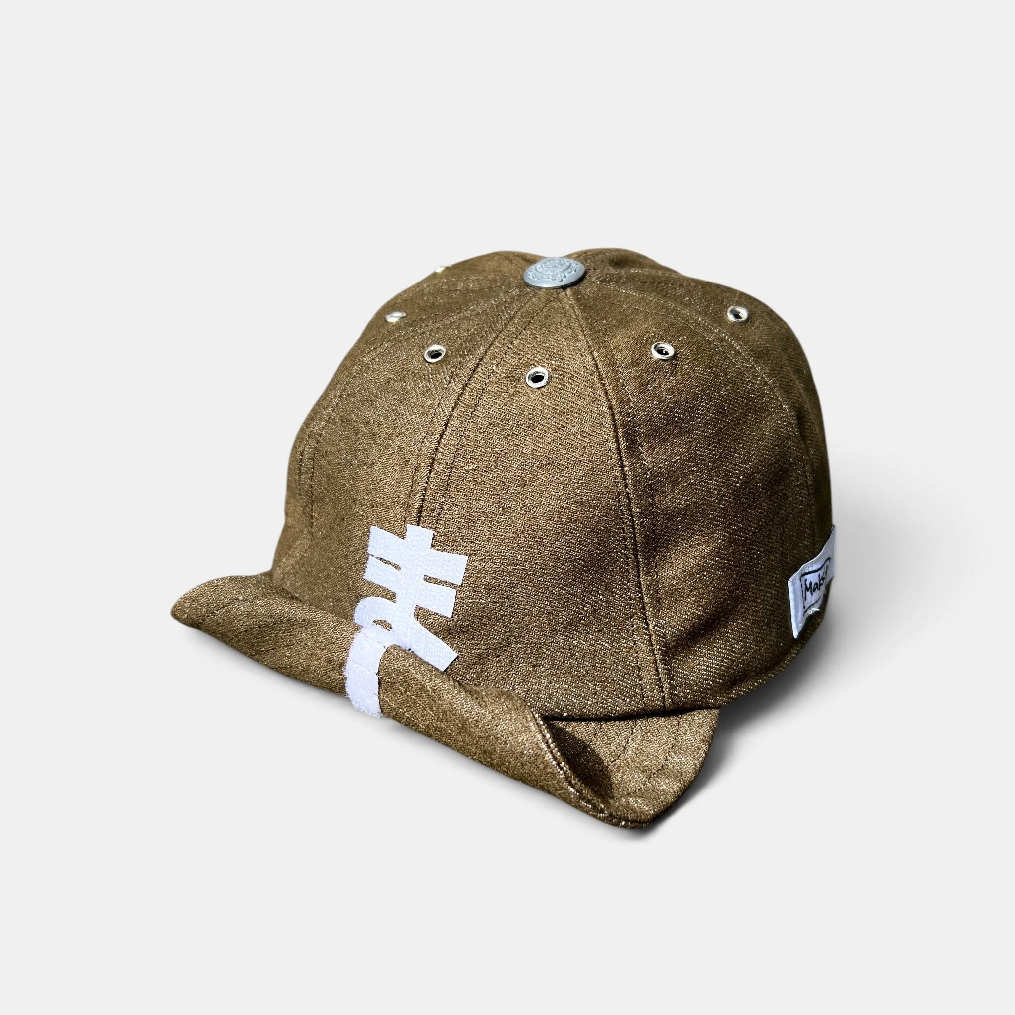 Olive-brown cotton denim cap with personalised white velcro motif and partially rolled-up visor
