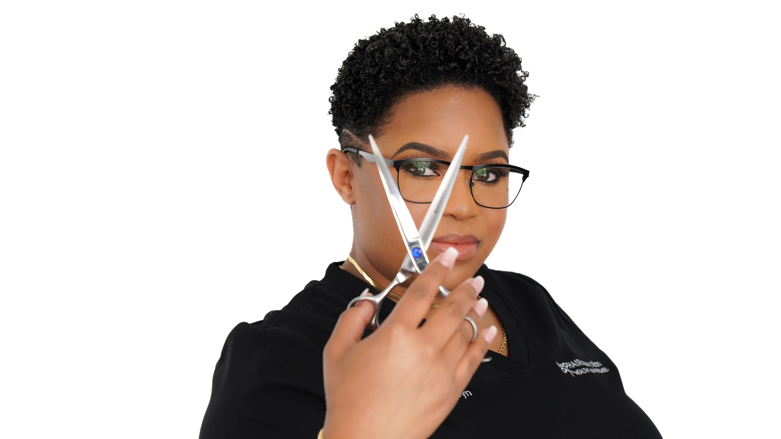 woman with short curly black hair, glasses, and black shirt holding a pair of scissors