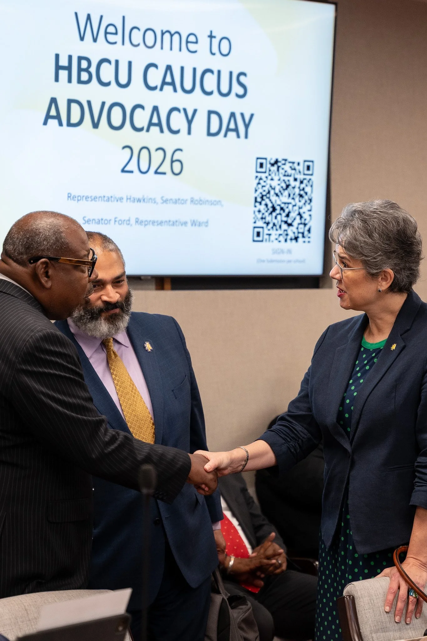 People shaking hands at an event with a sign in the background that reads 'Welcome to HBCU Caucus Advocacy Day 2026' and features a QR code.